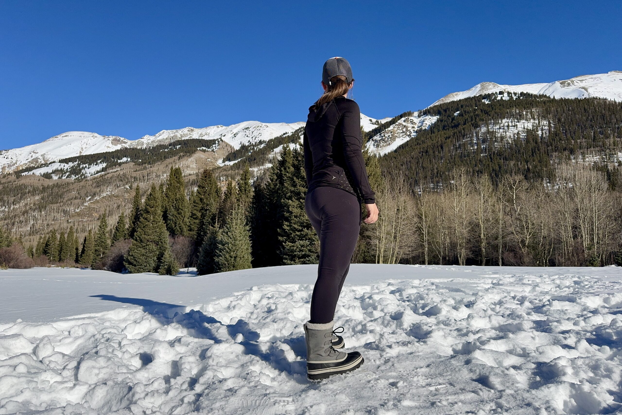 A person taking in a mountain view while wearing the Sorel boots in the snow.