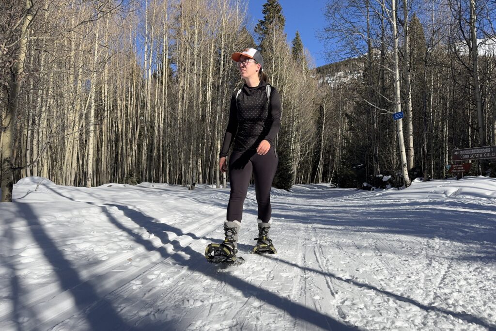 A person snowshoeing while wearing the Sorel boots in the woods.