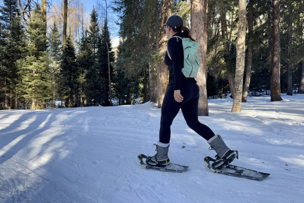 A person snowshoeing while wearing the Sorel boots in the woods.