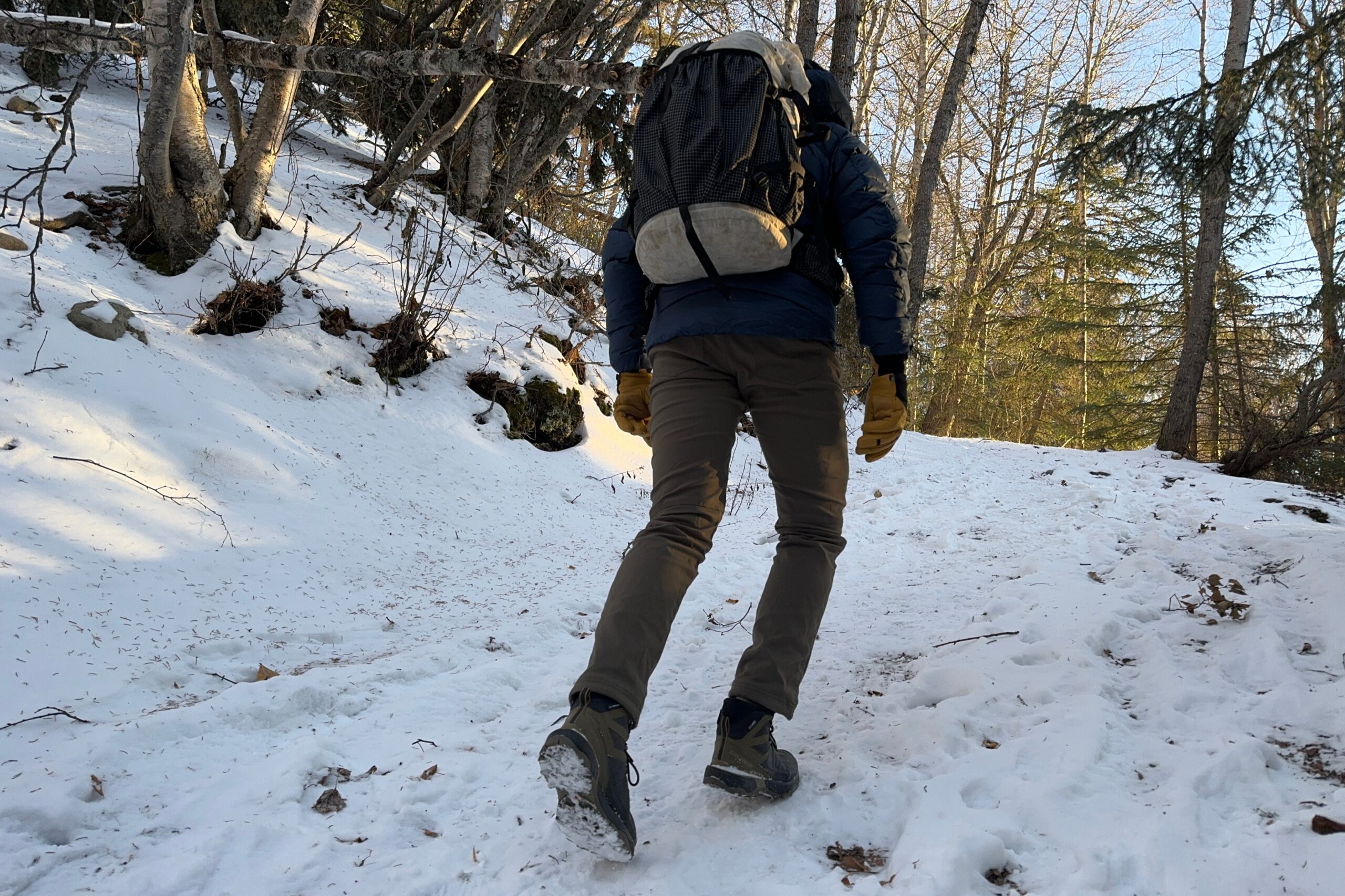 A rear shot of the soles of the boots of a man hiking uphill.