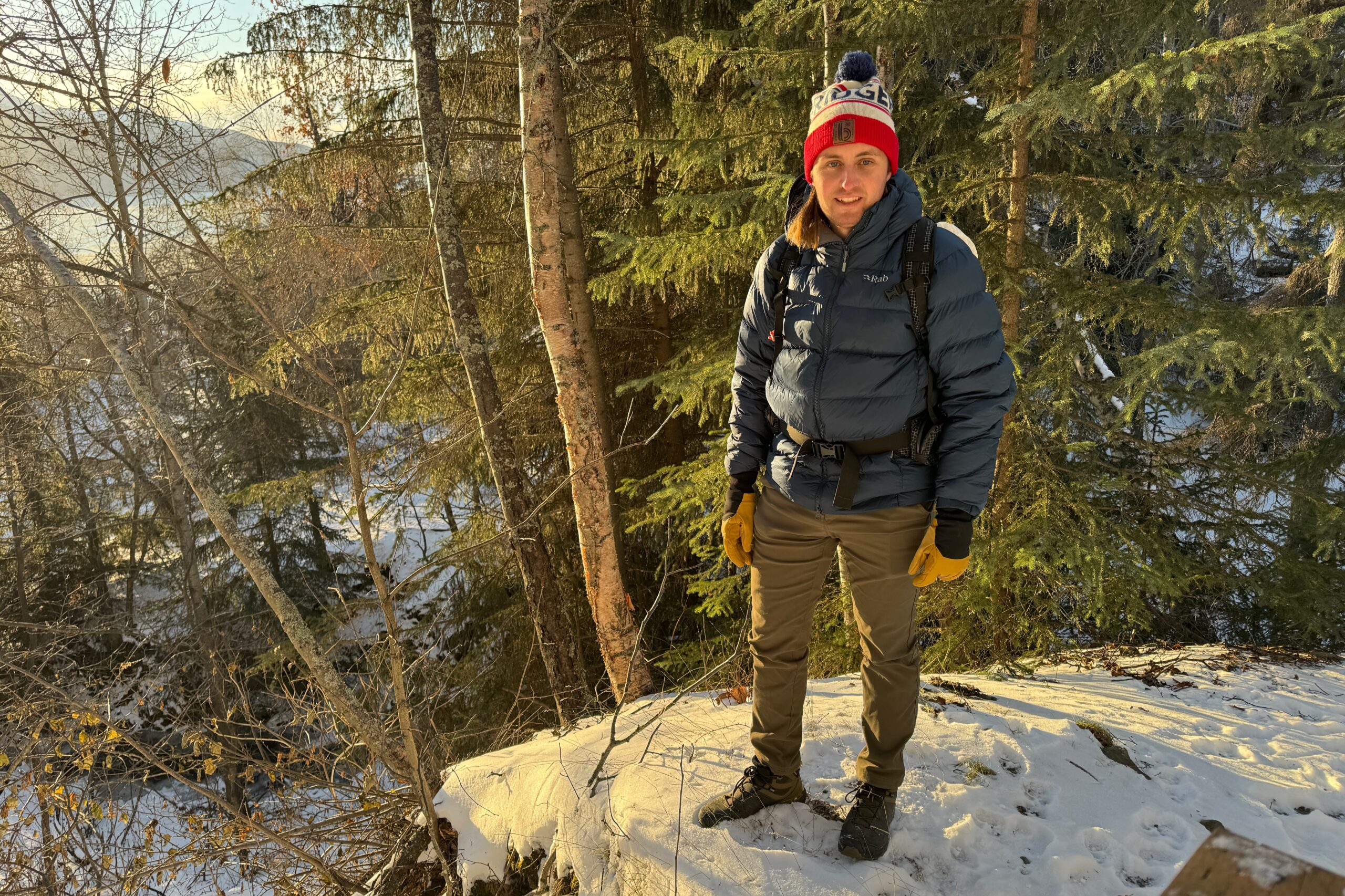 A man stands in evening light on a forest trail.