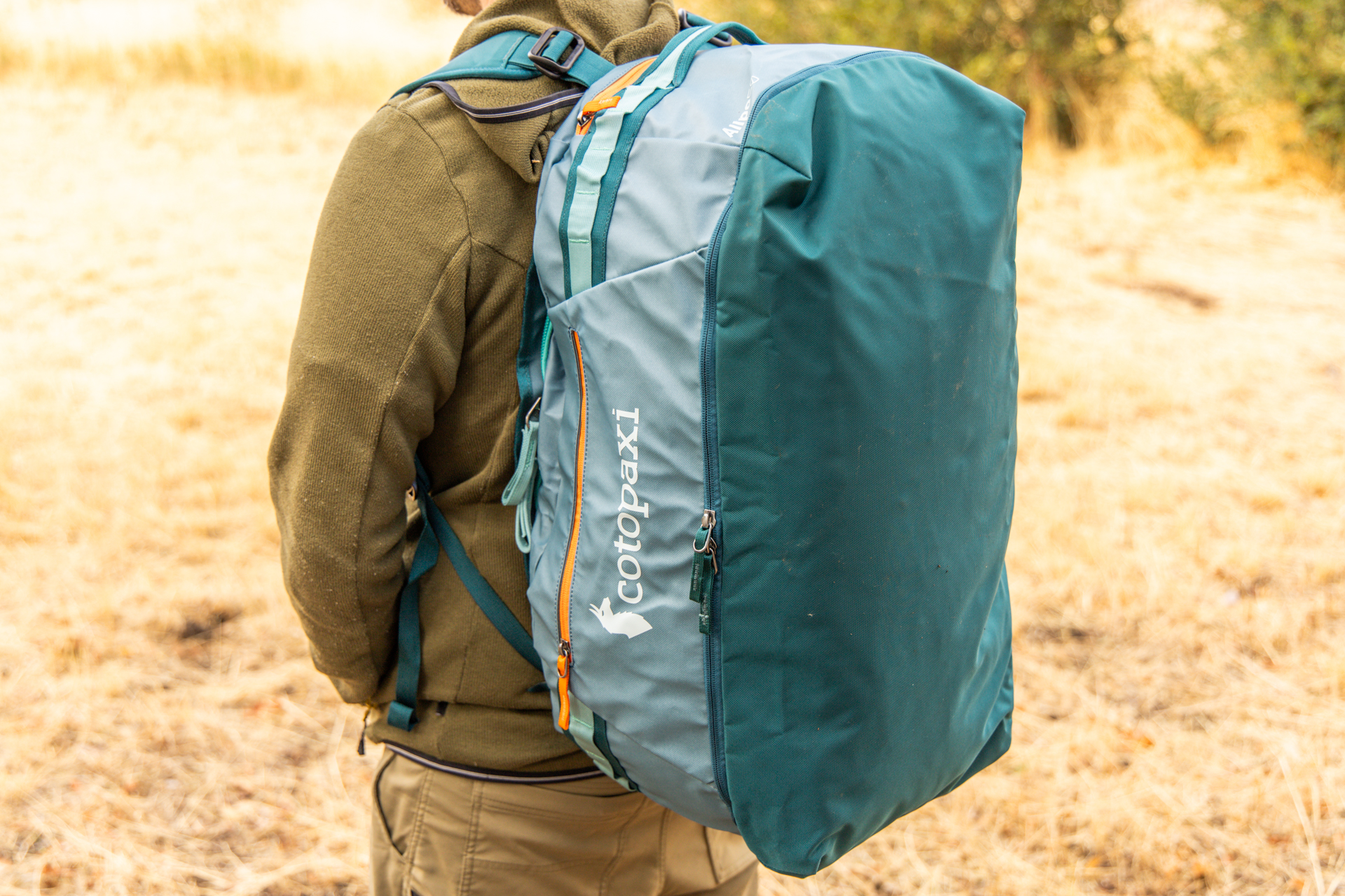 A man wears the Cotopaxi Allpa 50 duffel on his back in backpack mode.