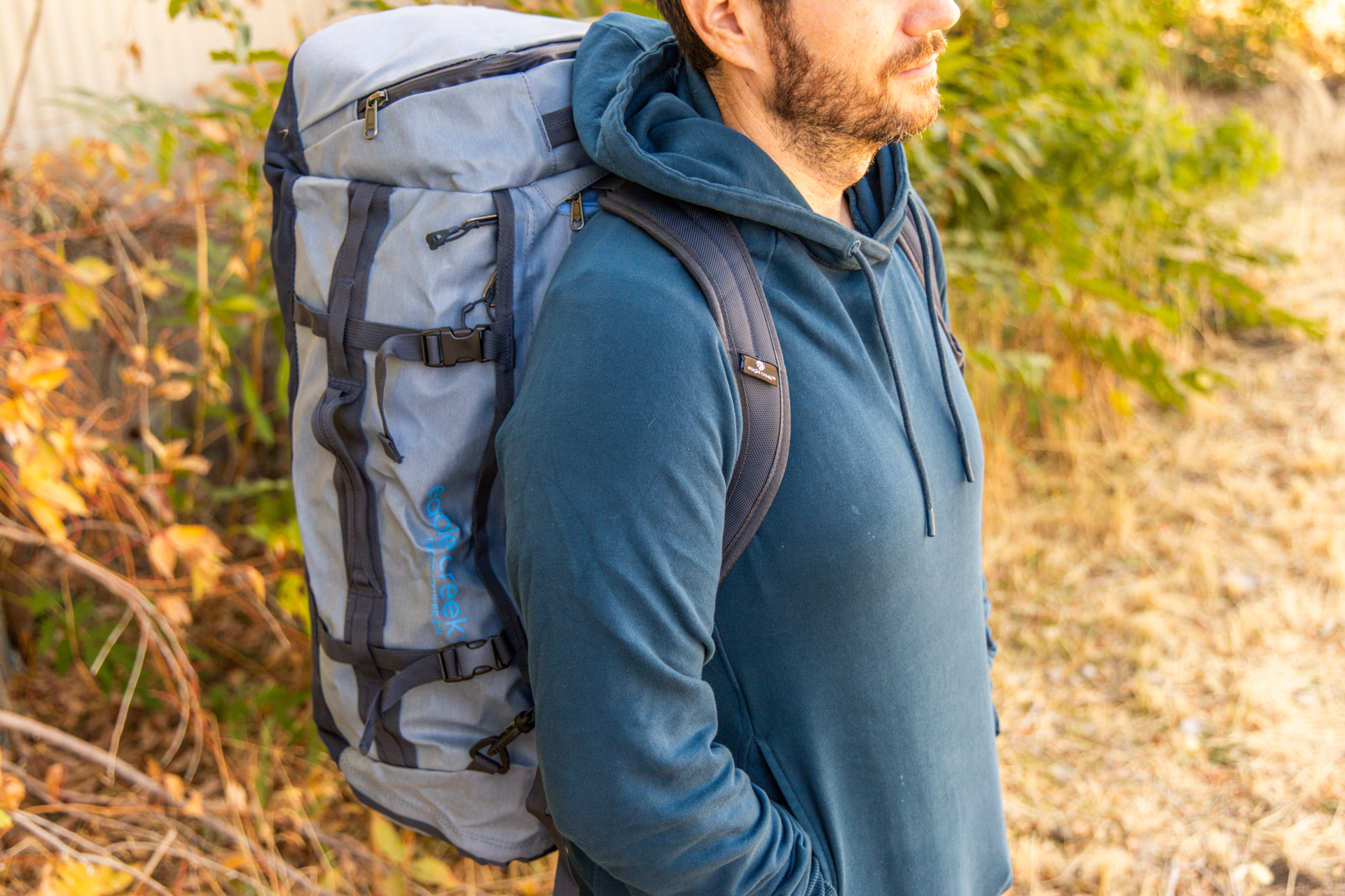 A man carries the Eagle Creek Cargo Hauler 60L duffel via its backpack straps.