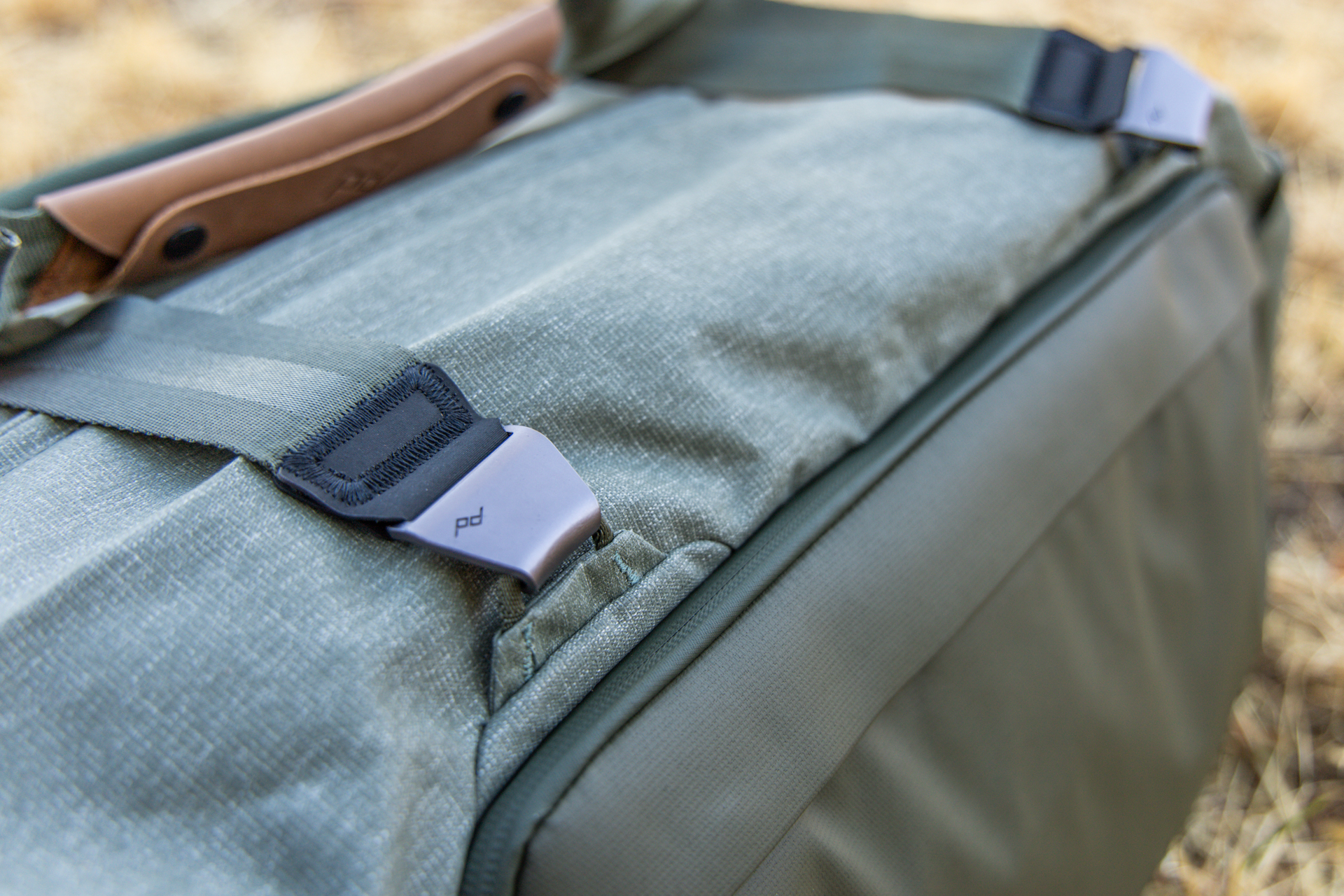 Durable metal hardware on the duffel handles strapped onto top attachment loops.