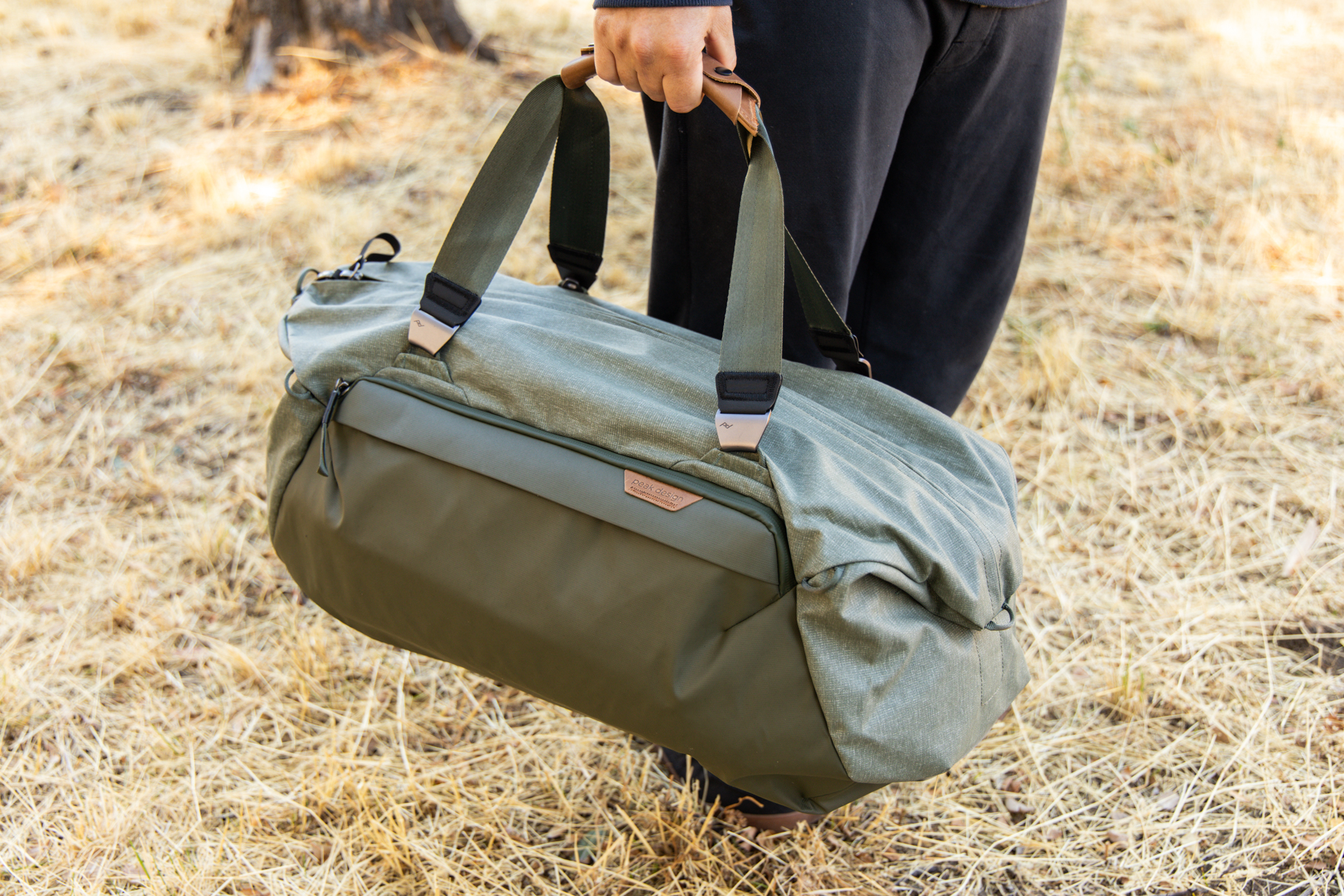 A man carries the Peak Design duffel using the traditional duffel straps.