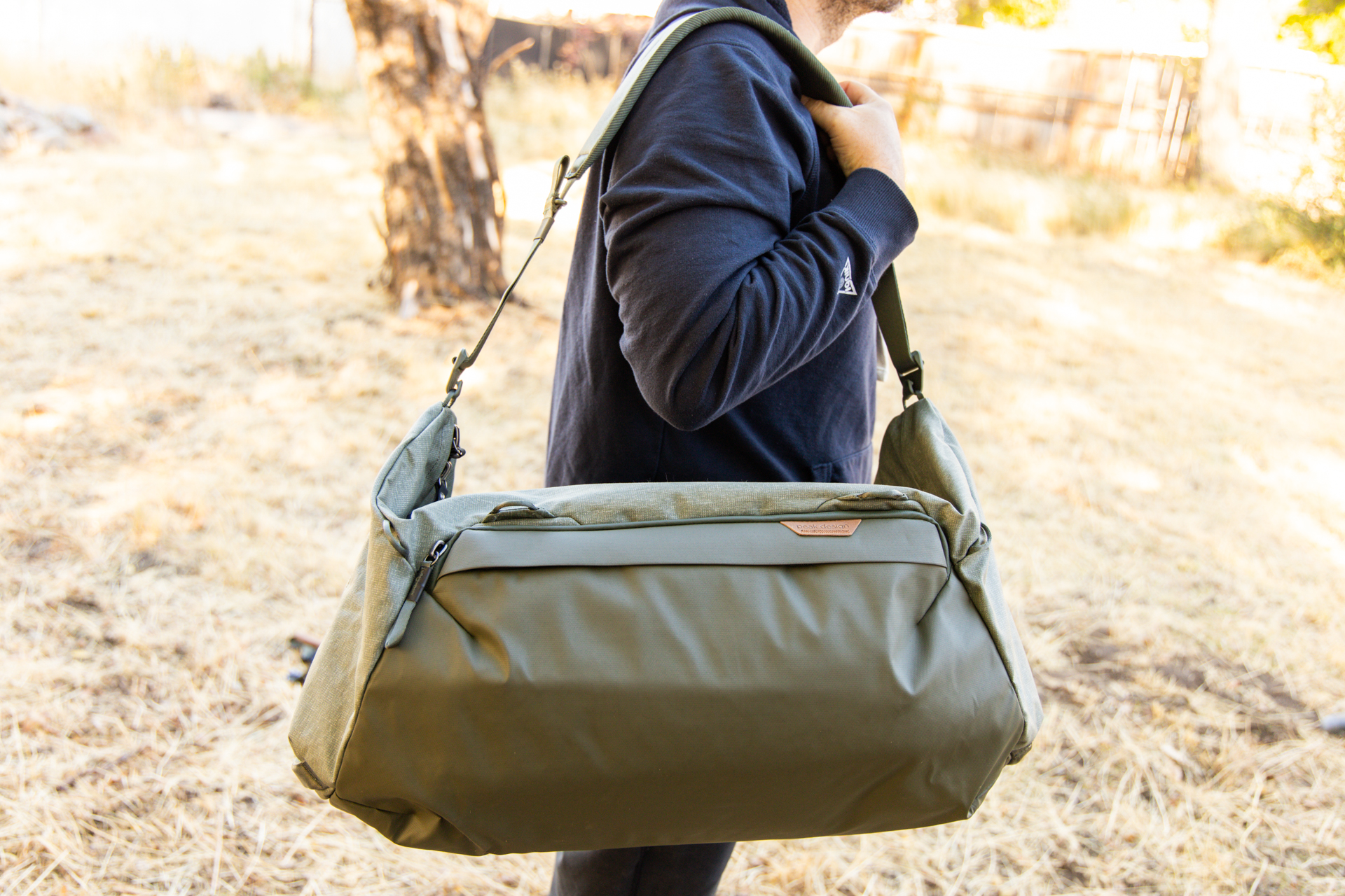 A man carries the Peak Design duffel over his shoulder using the padded shoulder strap.