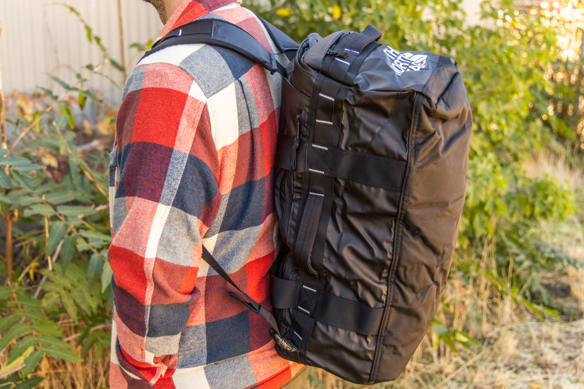 A man carrying the duffel like a backpack.