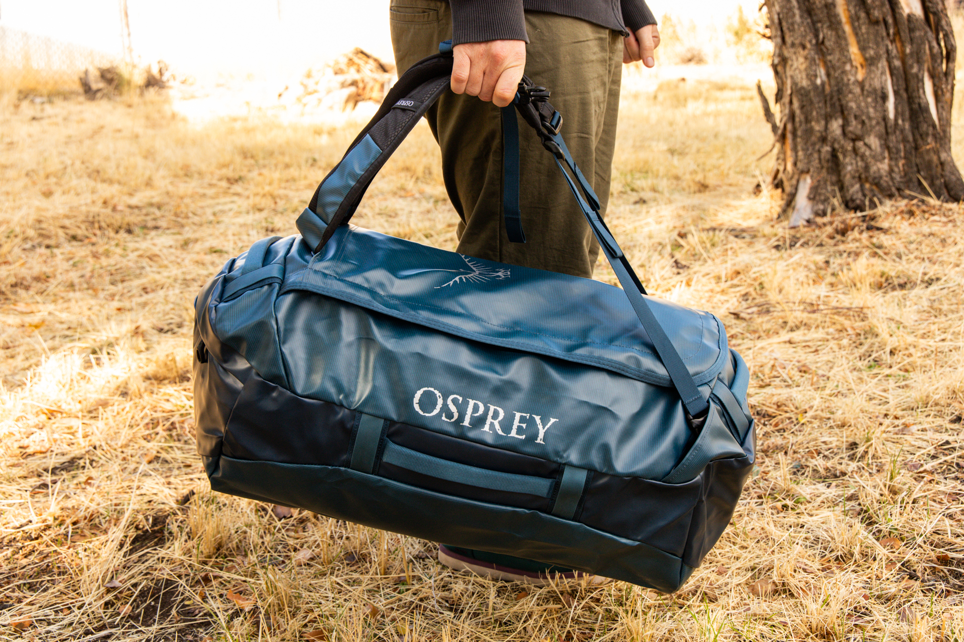 A man carrying the Osprey Transporter duffel using the shoulder straps as a grab handle.