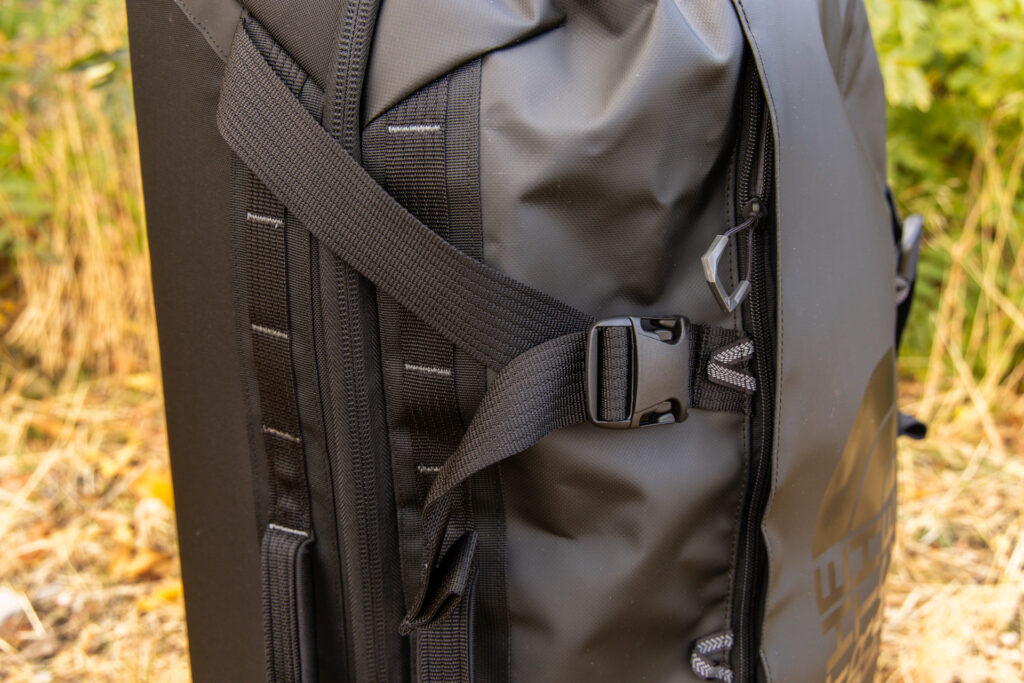 A close-up of the exterior compression strap buckles and front accessory pocket zipper.