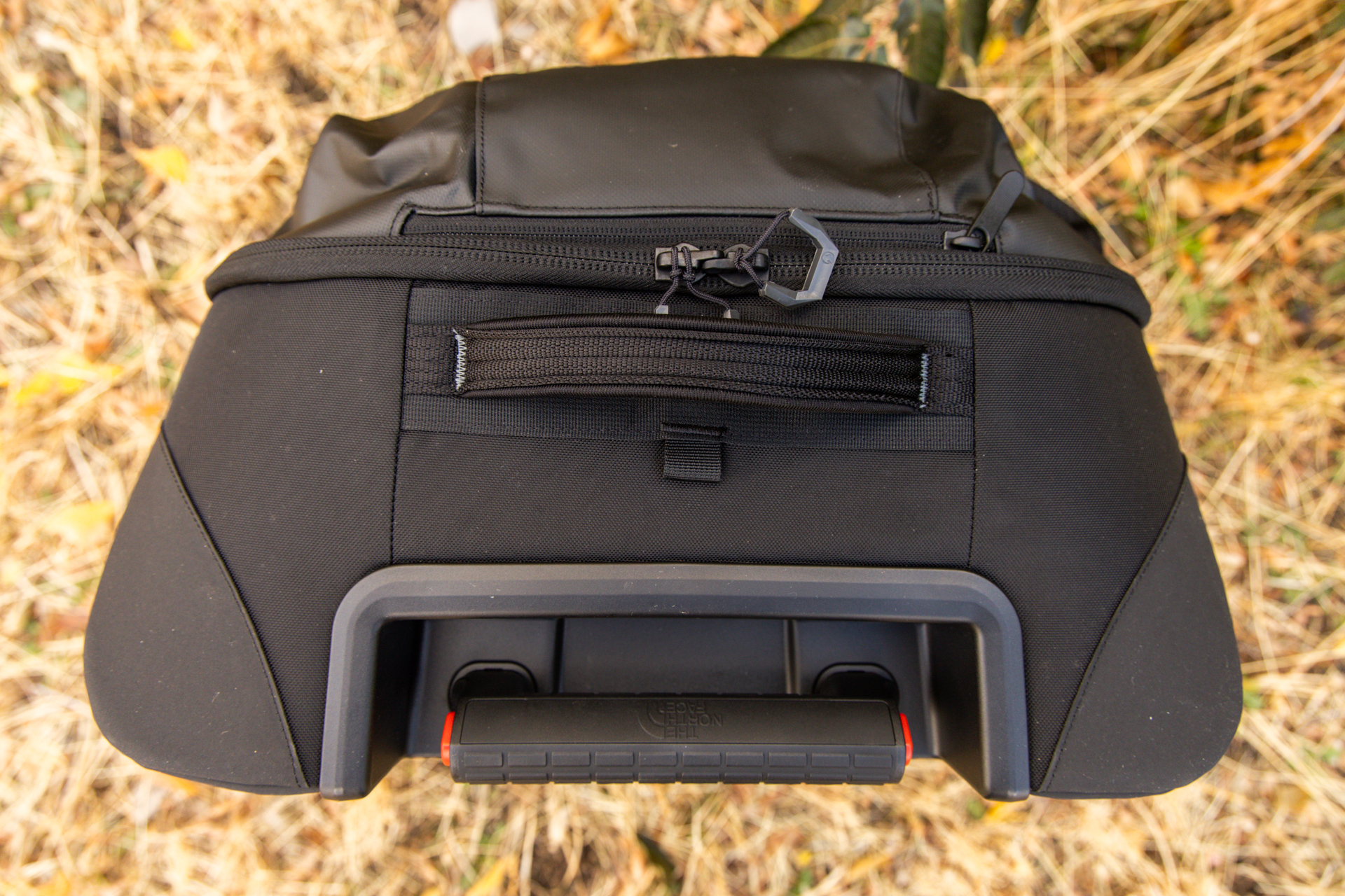 A top-down view of the top of the bag with handle retracted; there's also a comfortable grab handle on top and a small accessory pocket and loop for a sherpa strap.