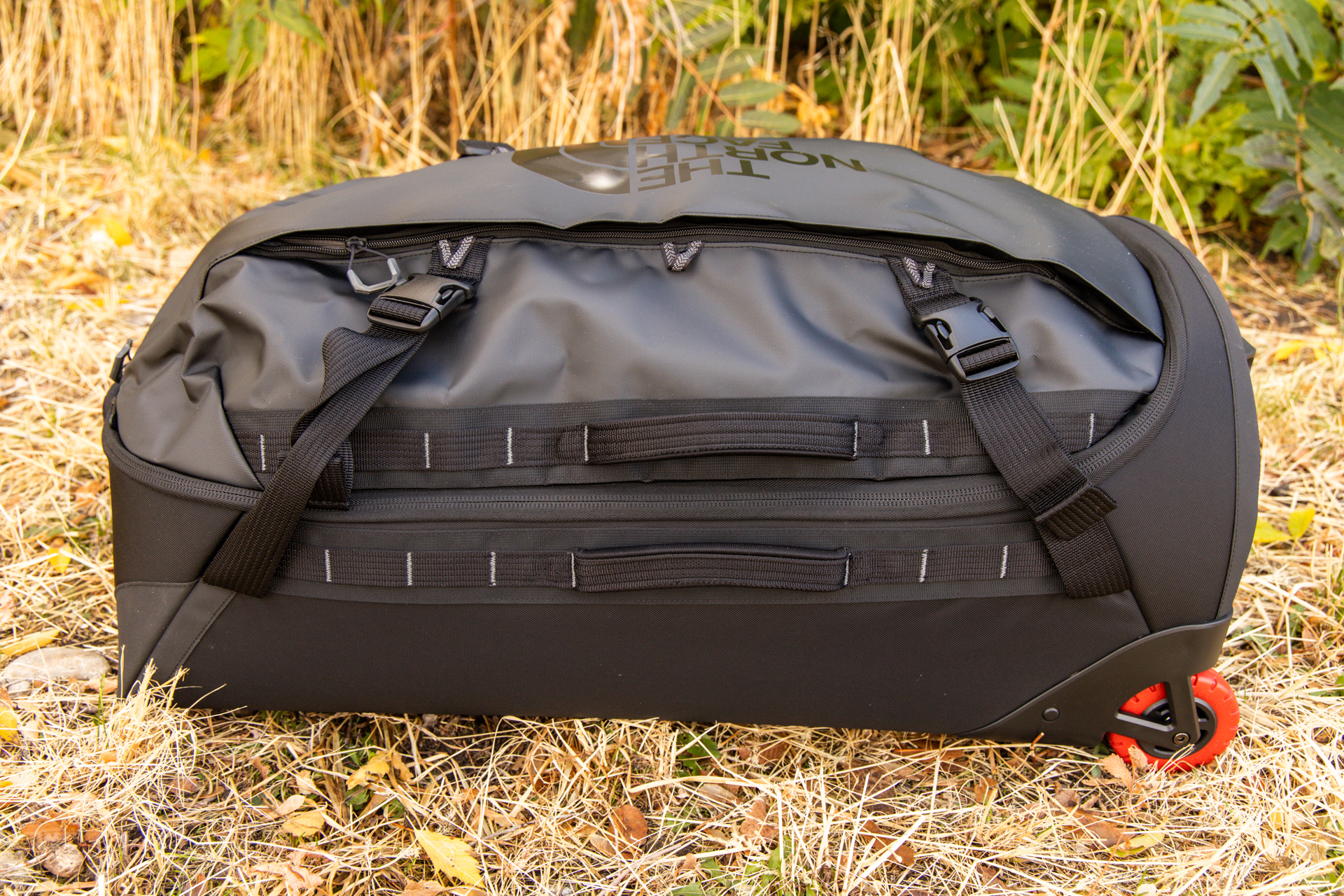 A side view of the bag laying on its back; you can see two padded grab handles--one on either side of the main zipper--compressions buckle straps, and front accessory pocket zipper.