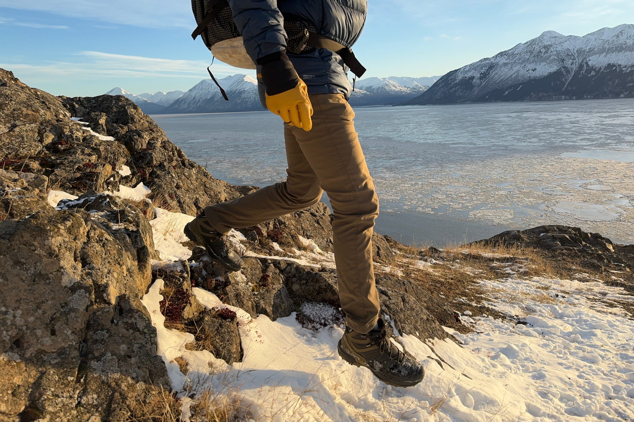 A closeup of a man taking a downhill step in snow.