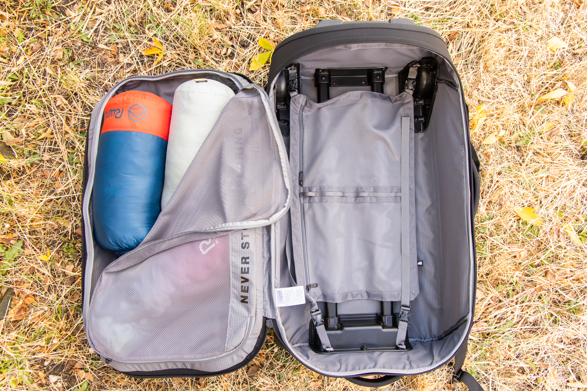 An open bag with an empty main compartment but several blankets visible from a half-opened compartment on the inside of the lid.