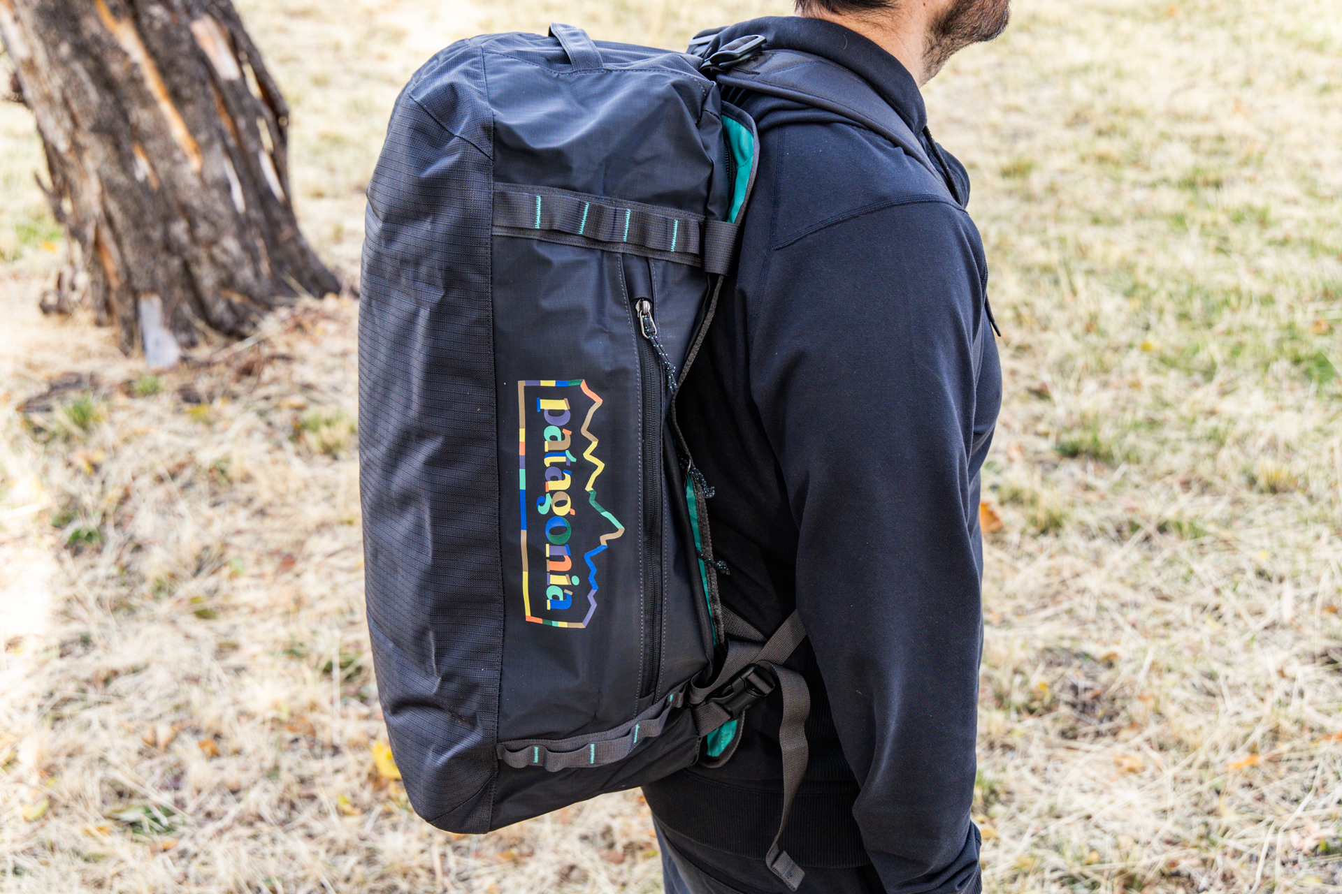 A man wears the Patagonia Black Hole as a backpack with the backpack straps attached.