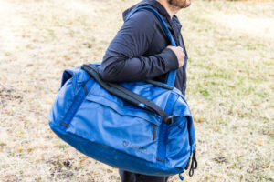 A man carries the Nemo Double Haul in duffel mode using the stowable tote handles.