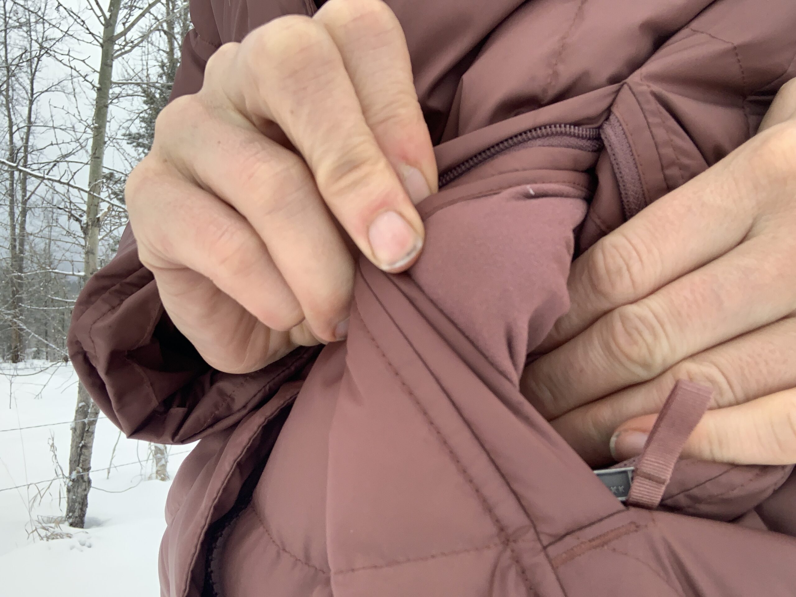 two hands opening and showing the soft liner on the pockets of the patagonia down with it parka