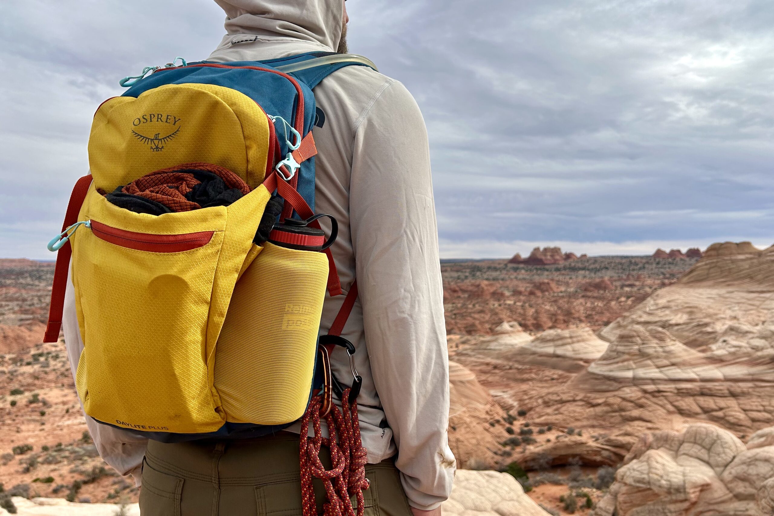 Close up of a daypack as a man looks into the distance in a desert landscape.