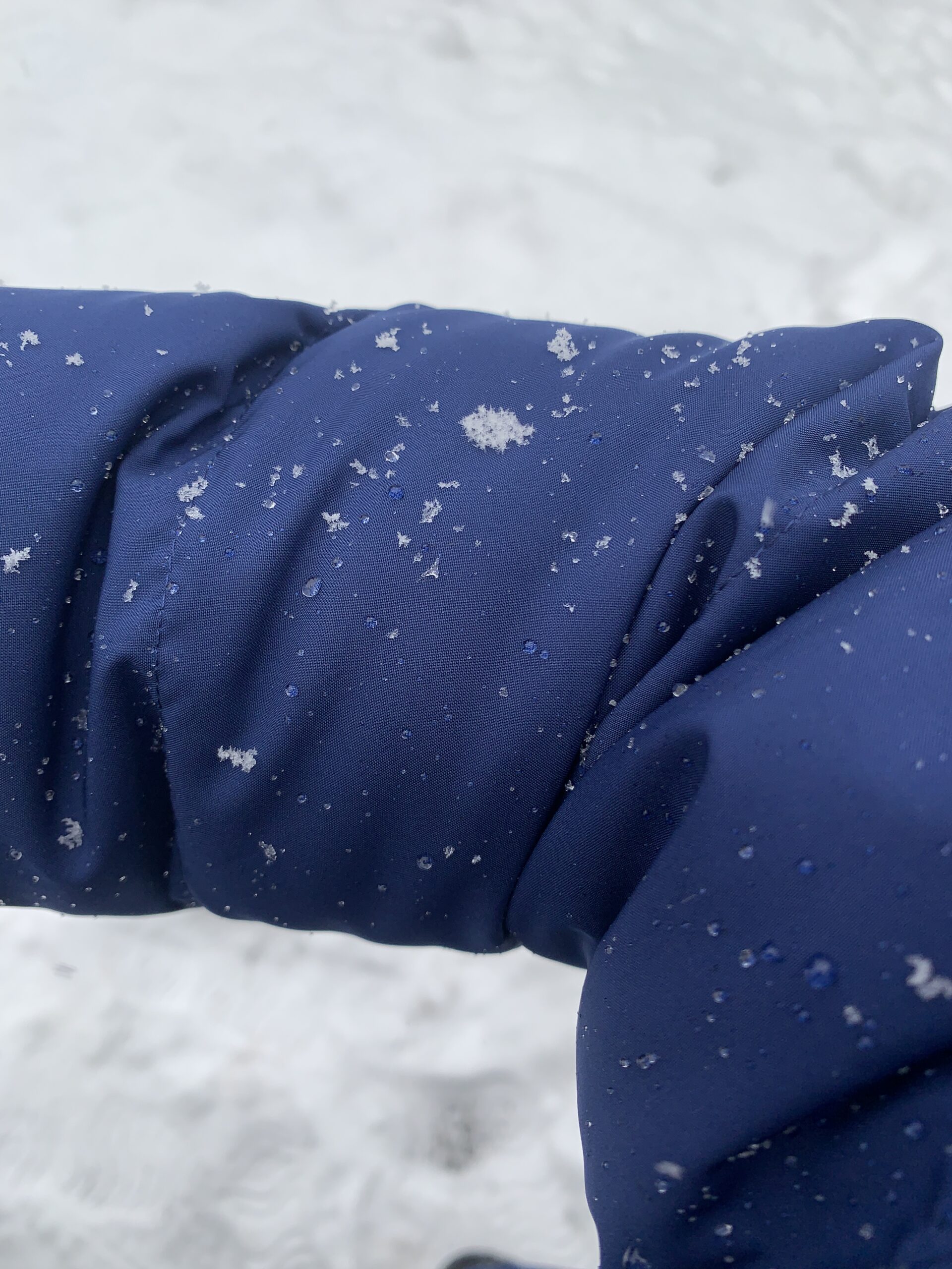 a close up of snow and water droplets on the sleeve of the llbean ultrawarm dow coat