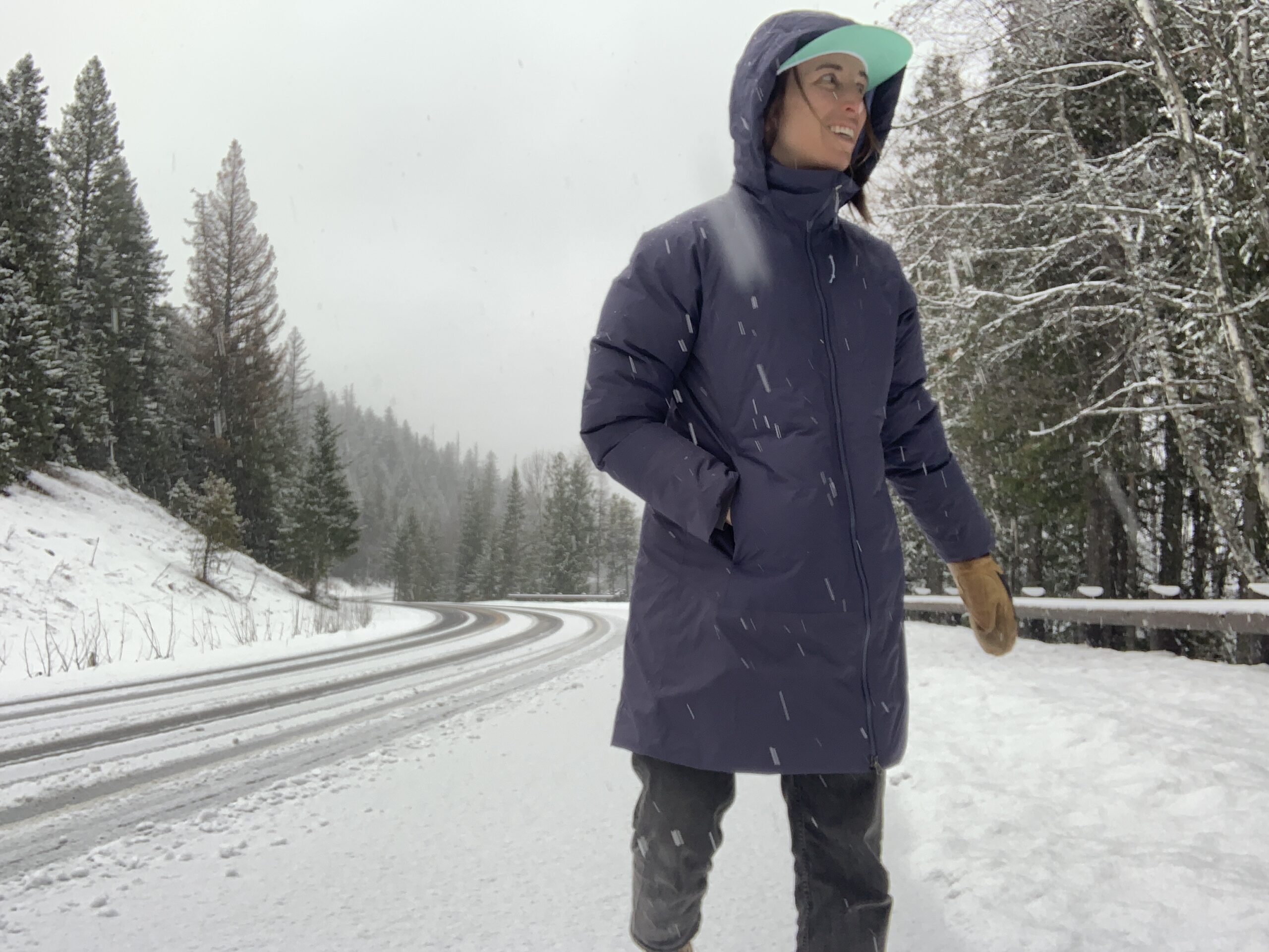 a woman smiles while walking in the snow on a snow covered road