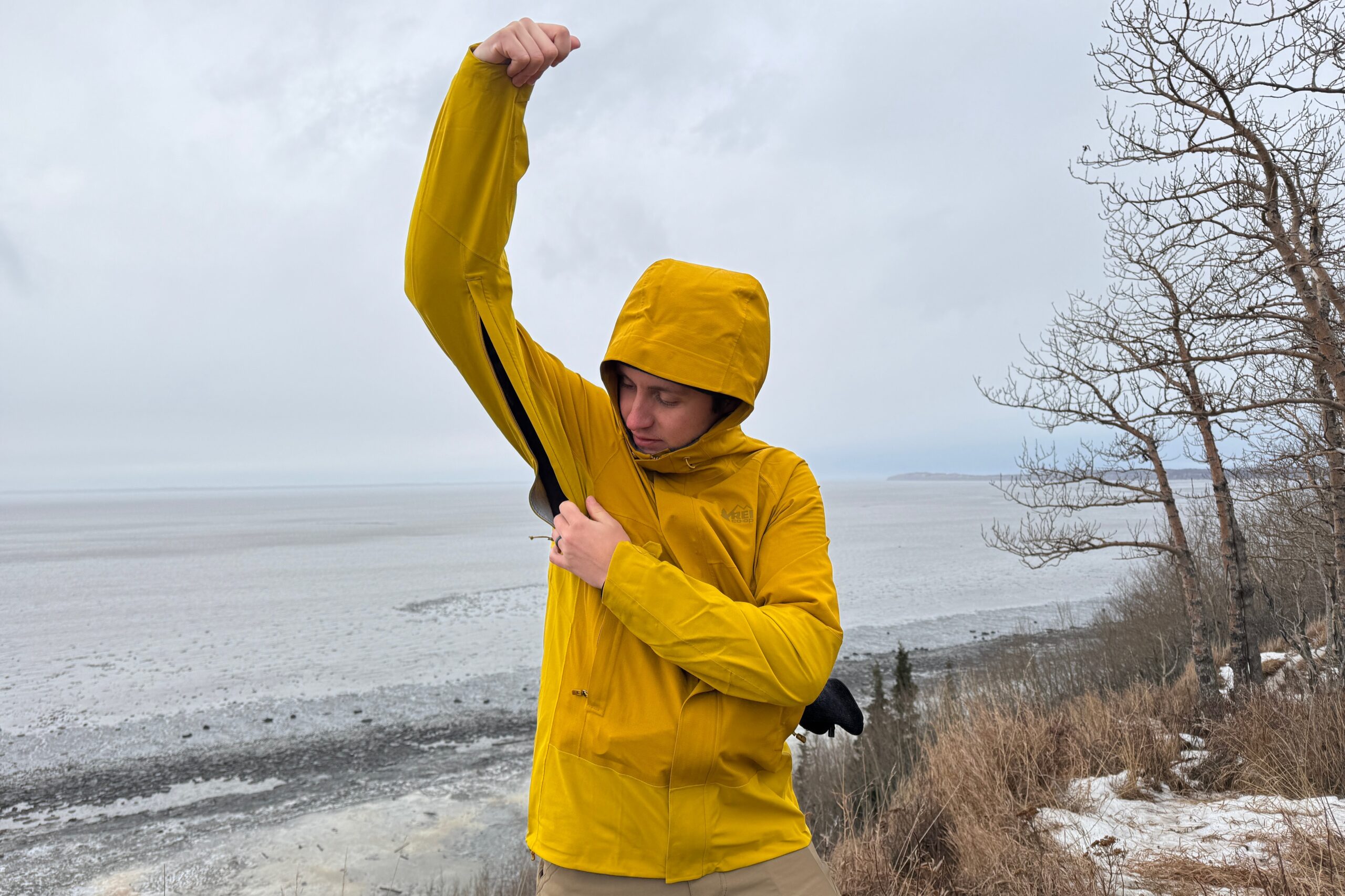 A man unzips the vent on his rain jacket.