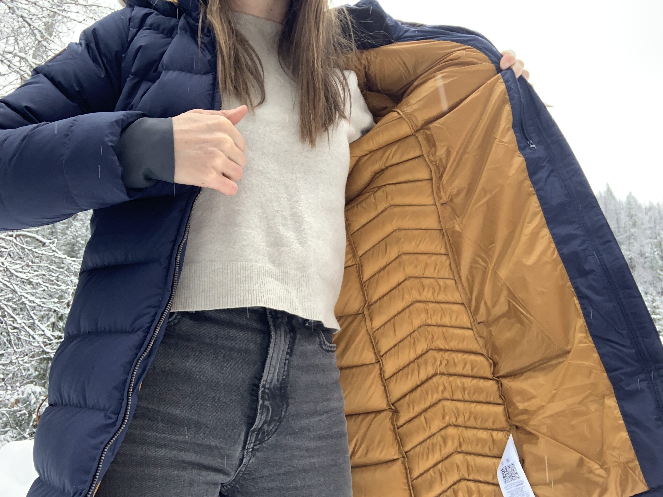 a woman showing the inside of the RAB deep cover parka