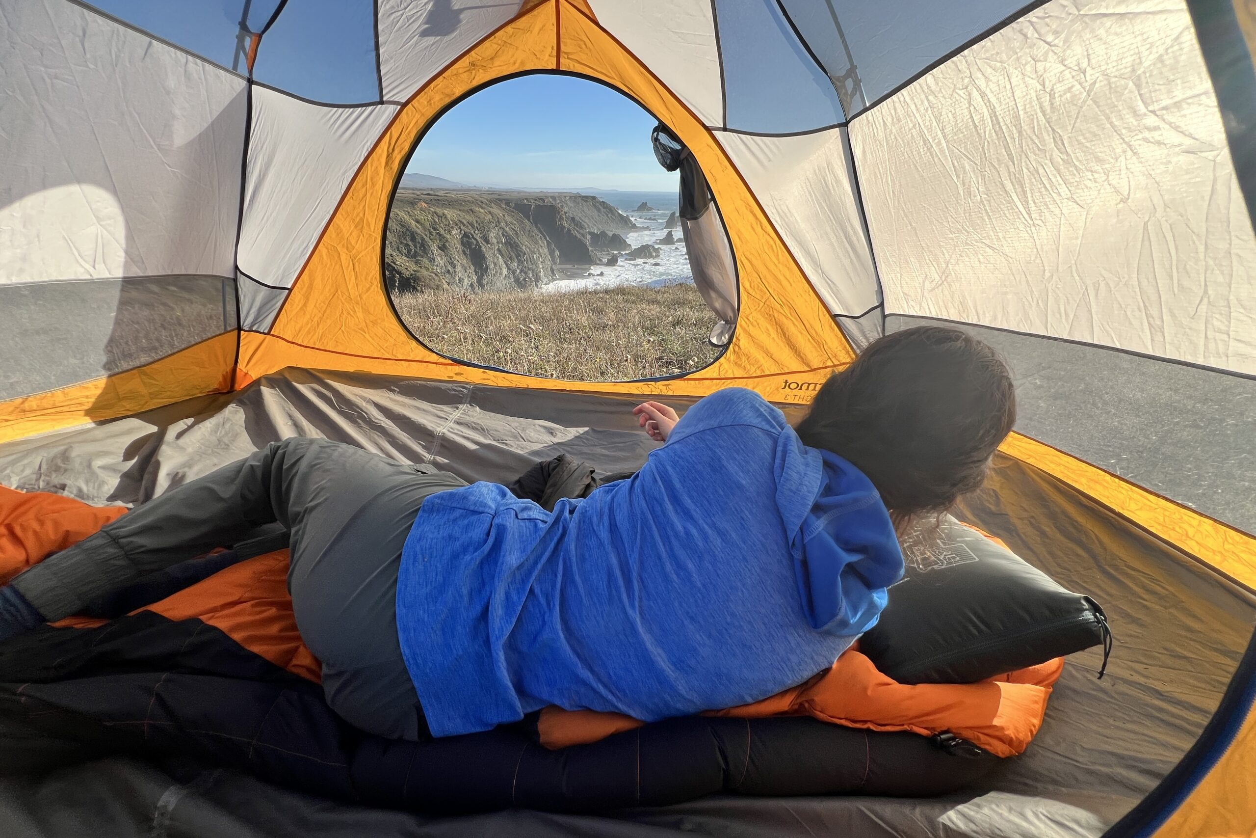 Woman laying in her tent using the Therm-a-Rest Honcho Poncho as a pillow