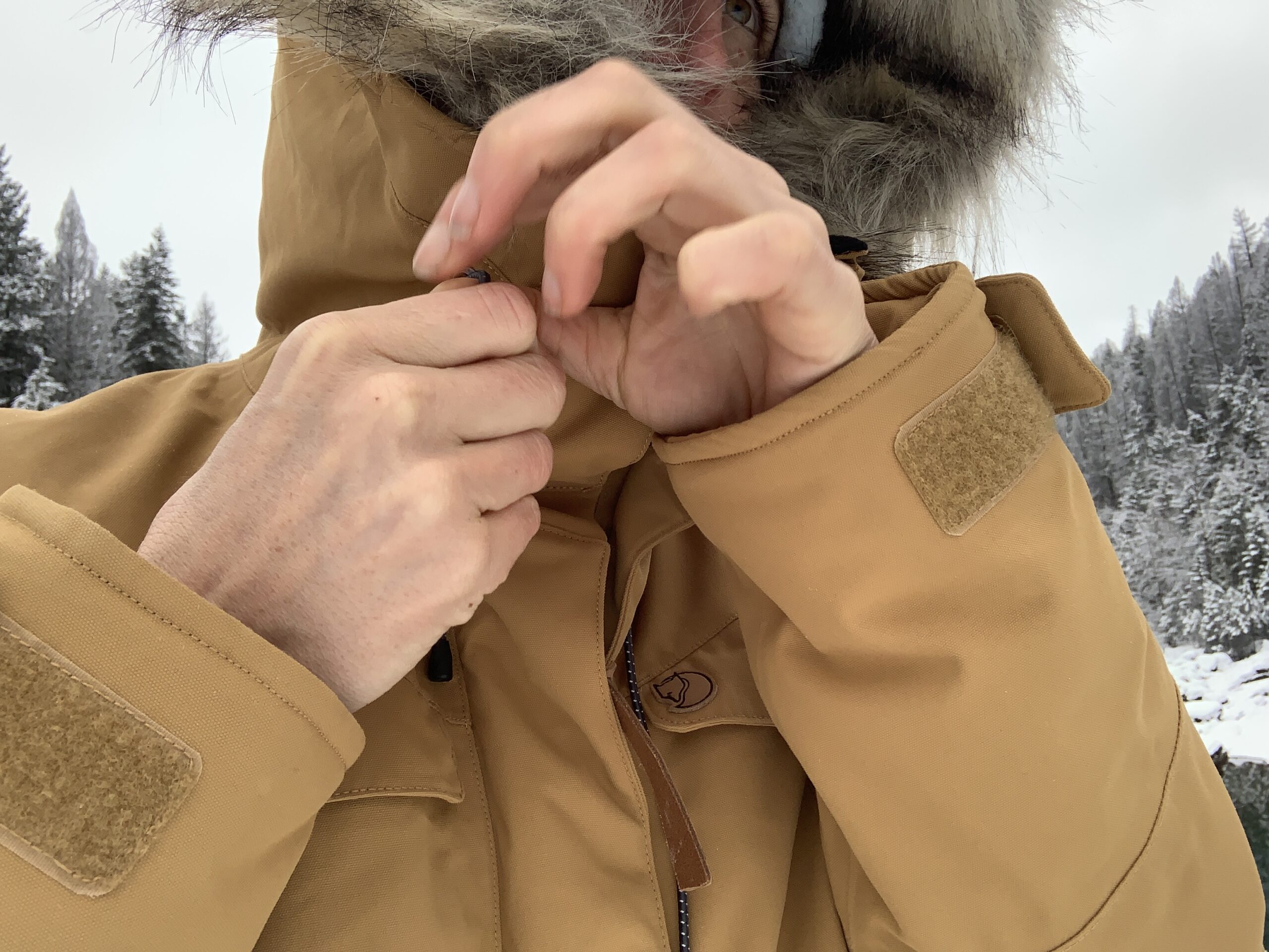 a woman cinches the hood of the fjallraven nuuk