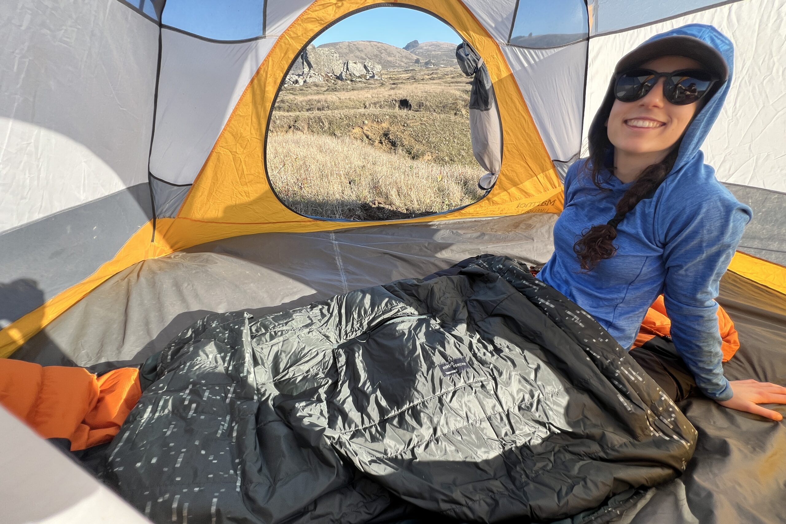 Woman laying in her tent using the Therm-a-Rest Honcho Poncho in its blanket form.