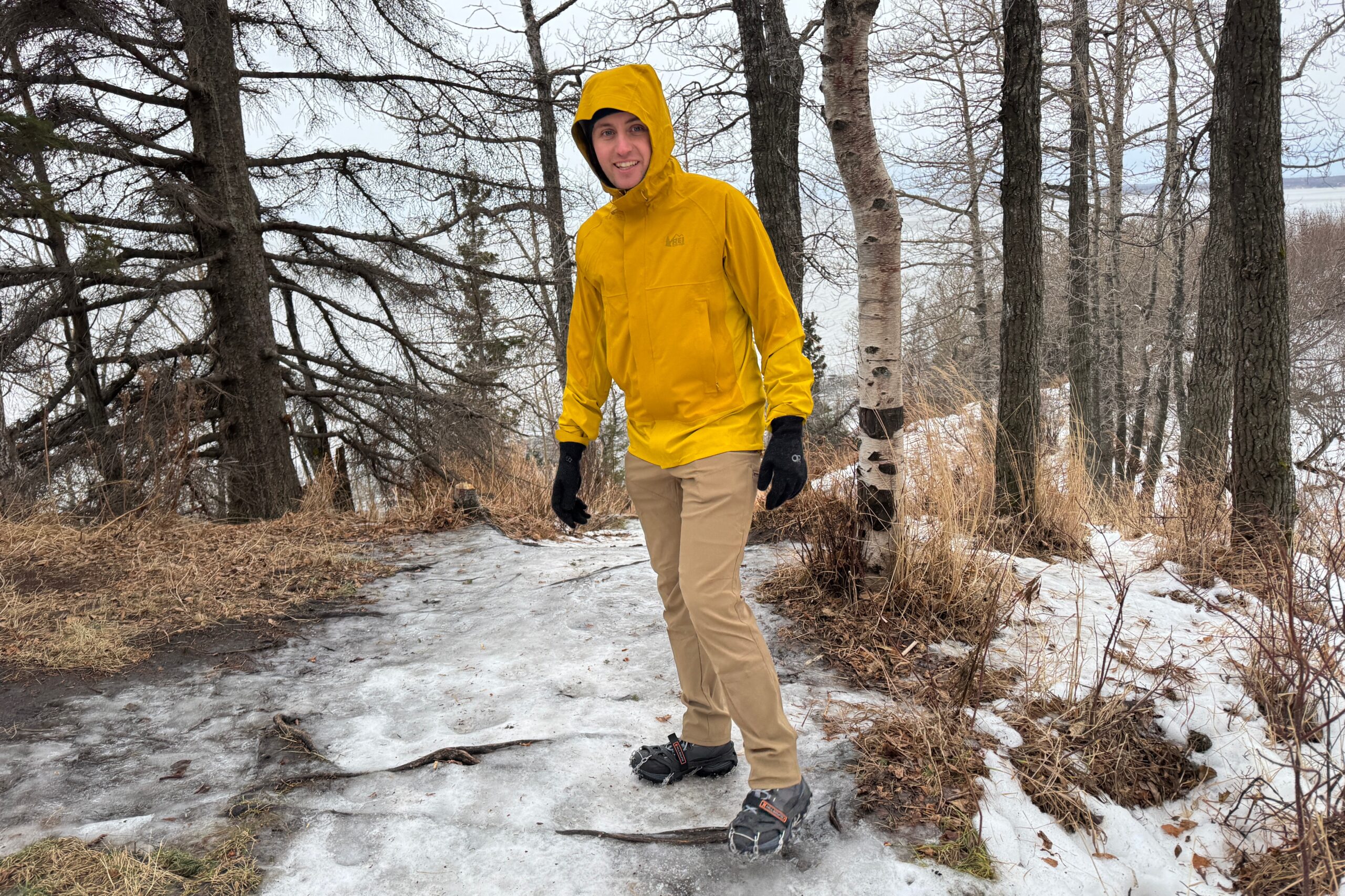 A man in a yellow rain jacket on a bluff over the ocean.