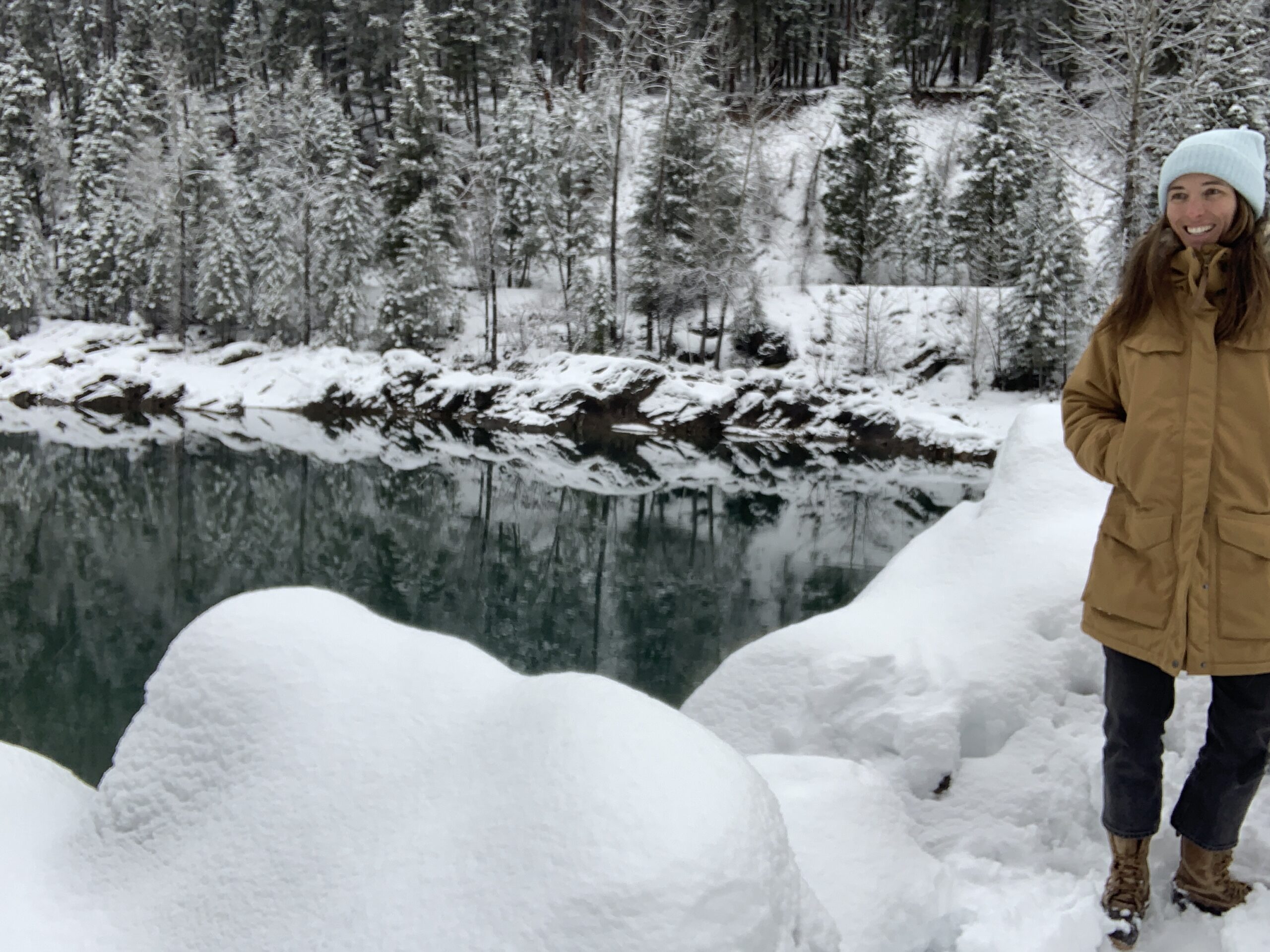 a woman posing in front of a river in montana while wearing the fjallraven nuuk