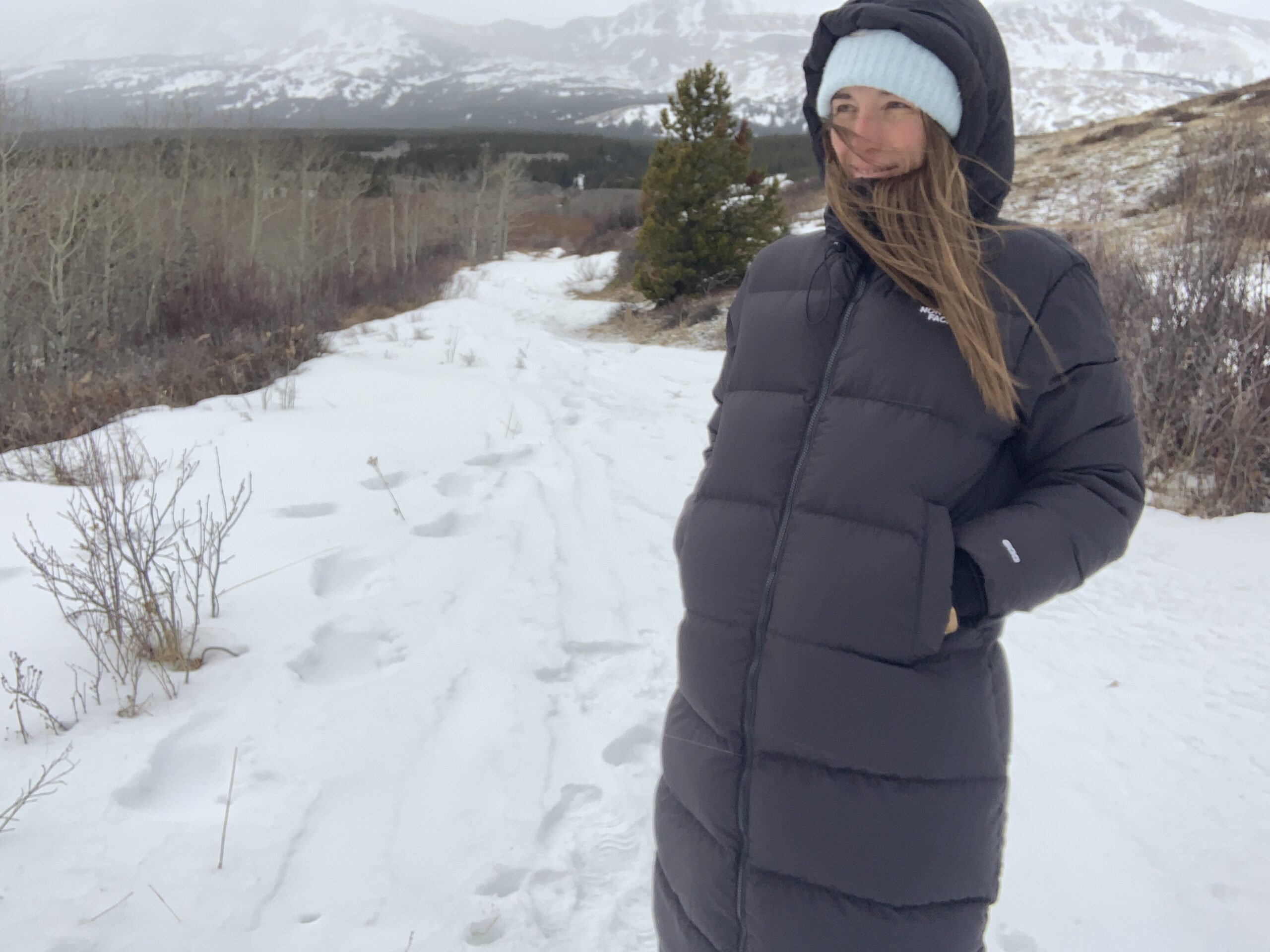 a woman stopped on a snowy trail wearing the full coverage north face triple c parka