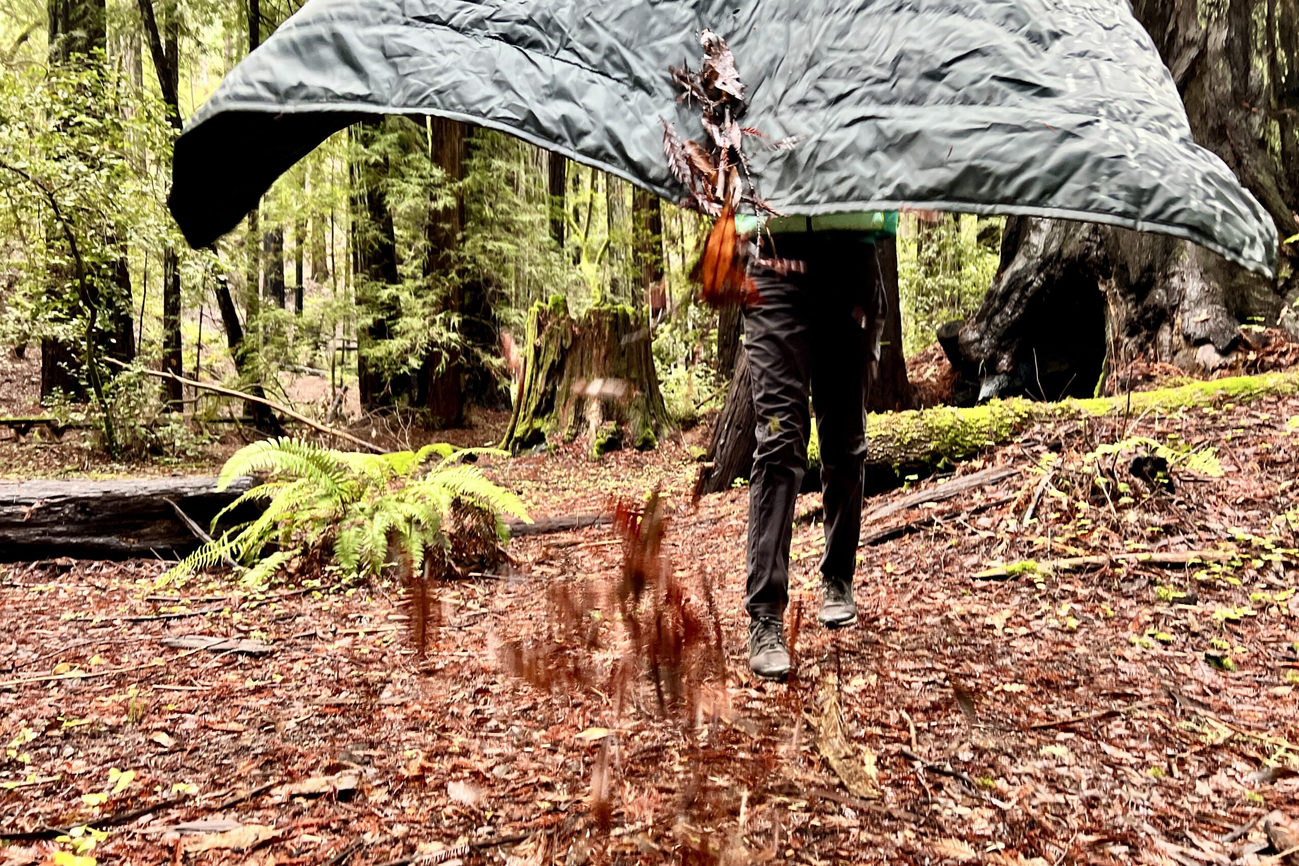 Person shaking debris off of the Therm-a-Rest Honcho Poncho.