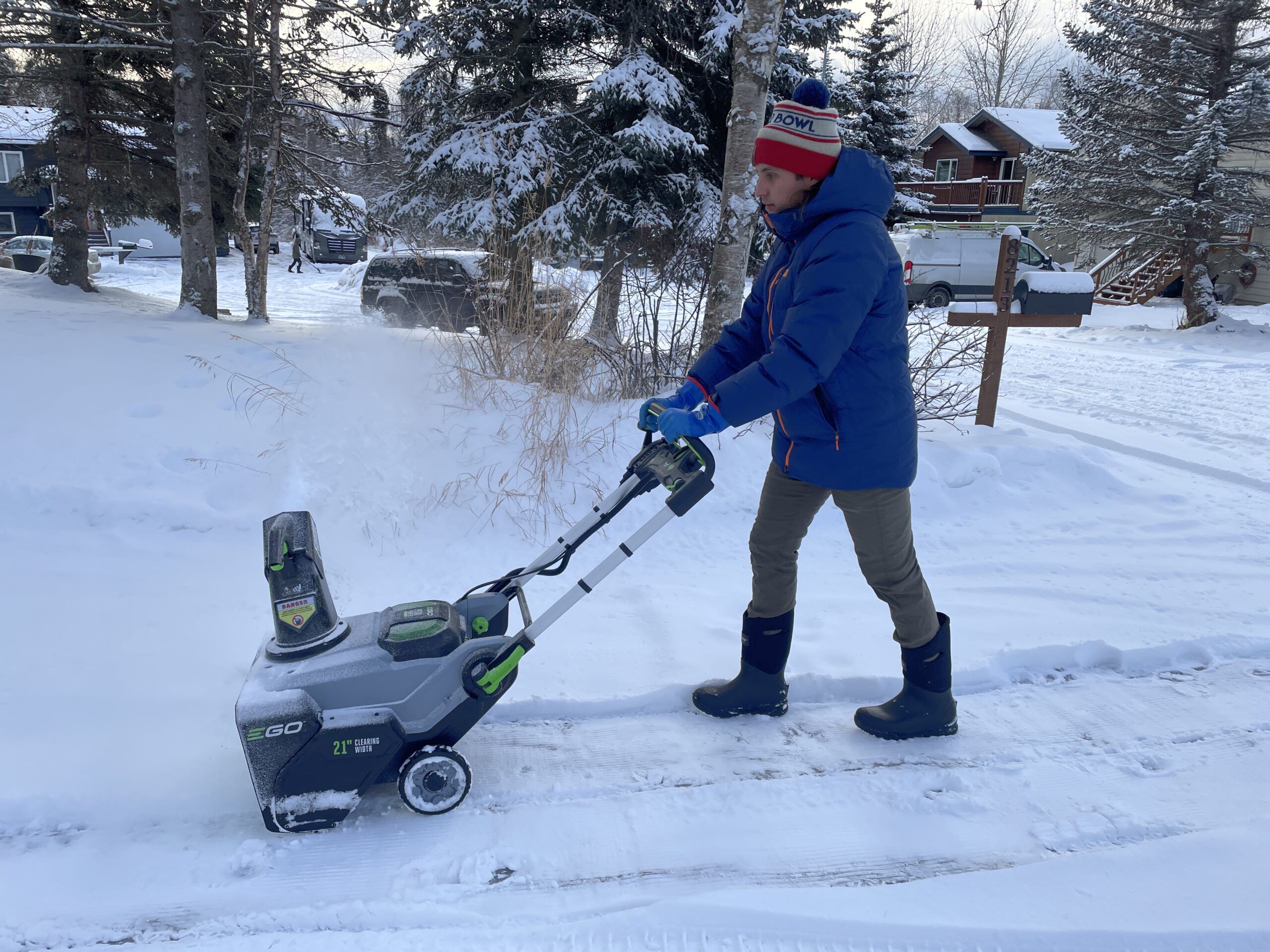 A man snow blows a driveway.