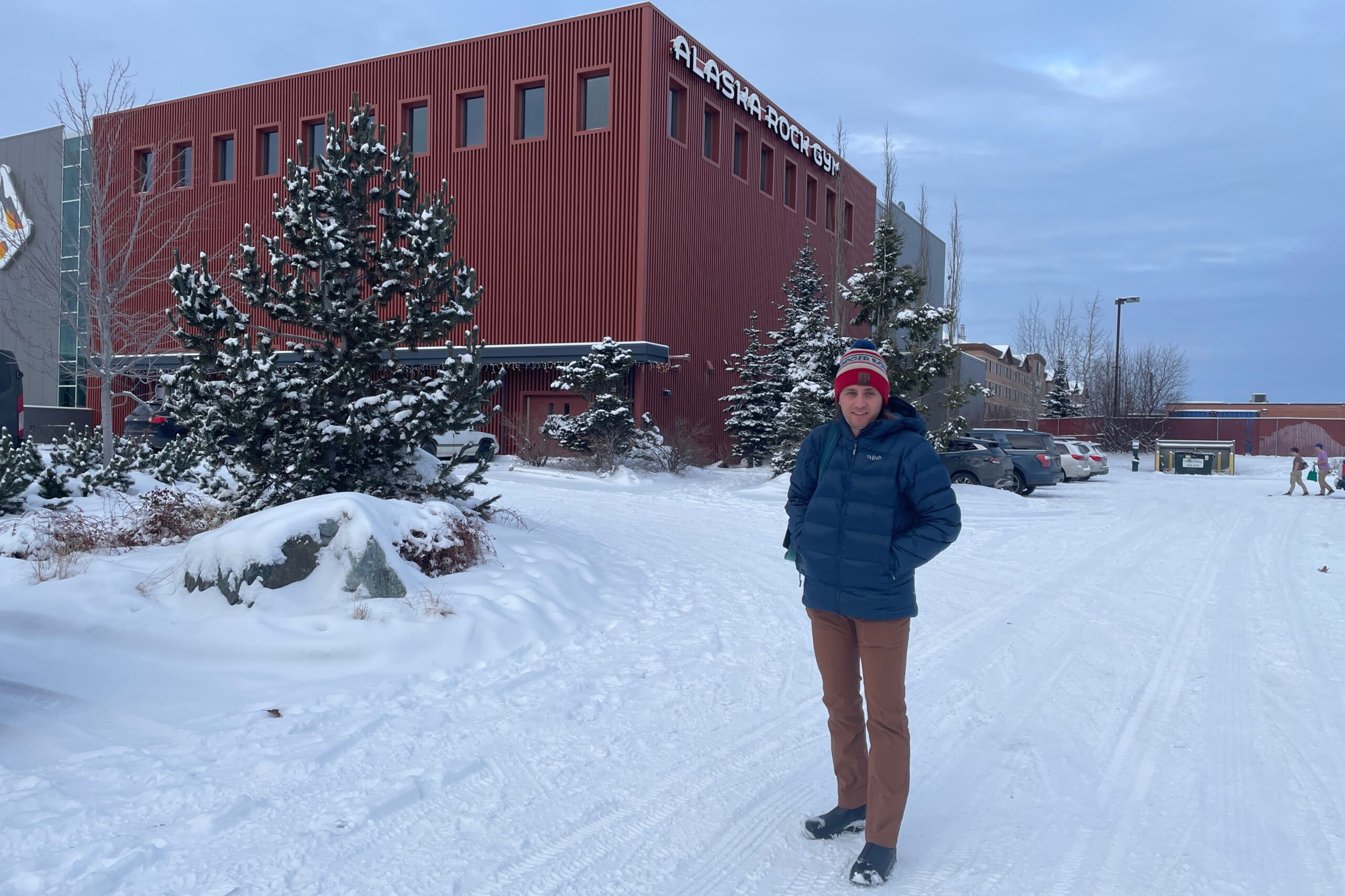 A man walks across a snowy parking lot.