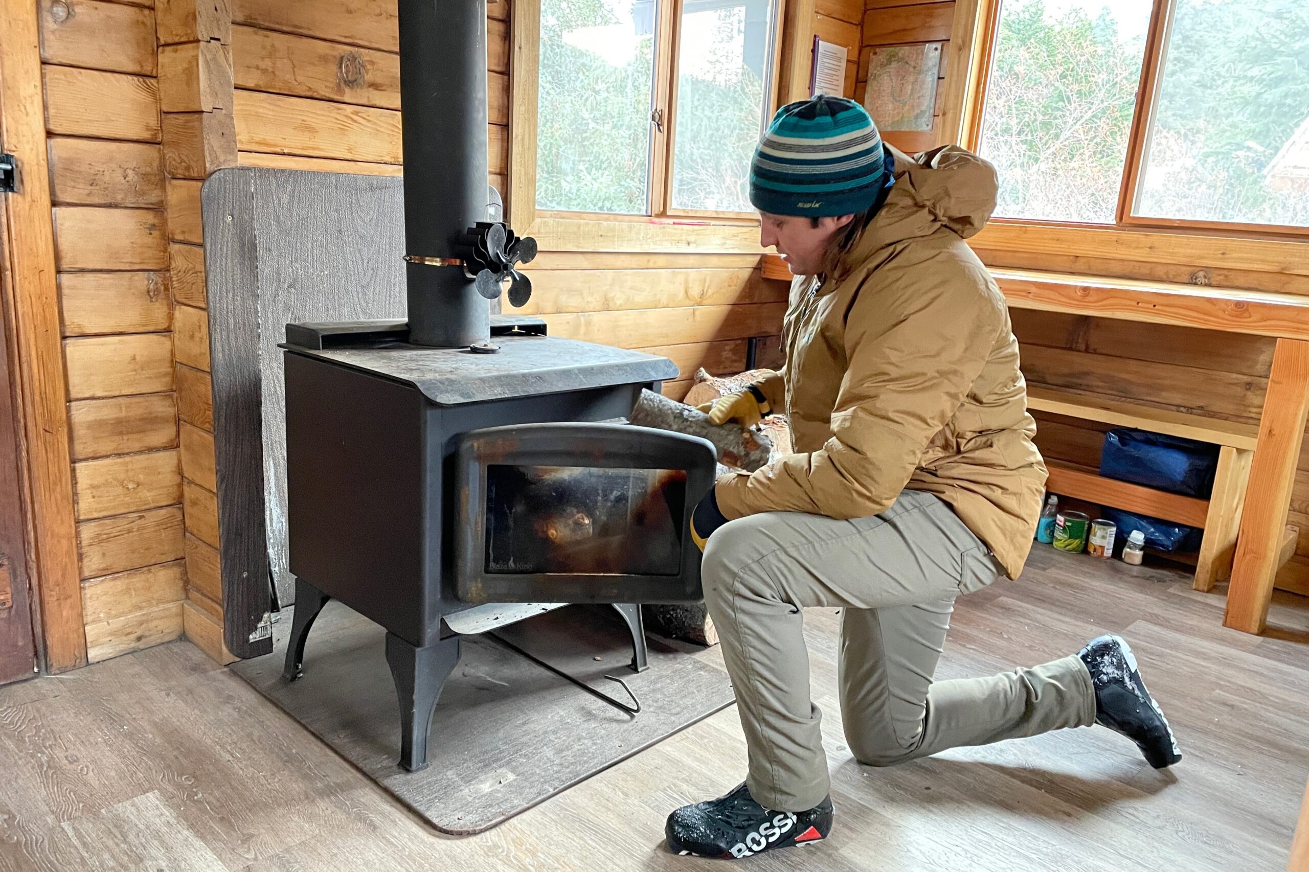 A man puts firewood in a woodstove.