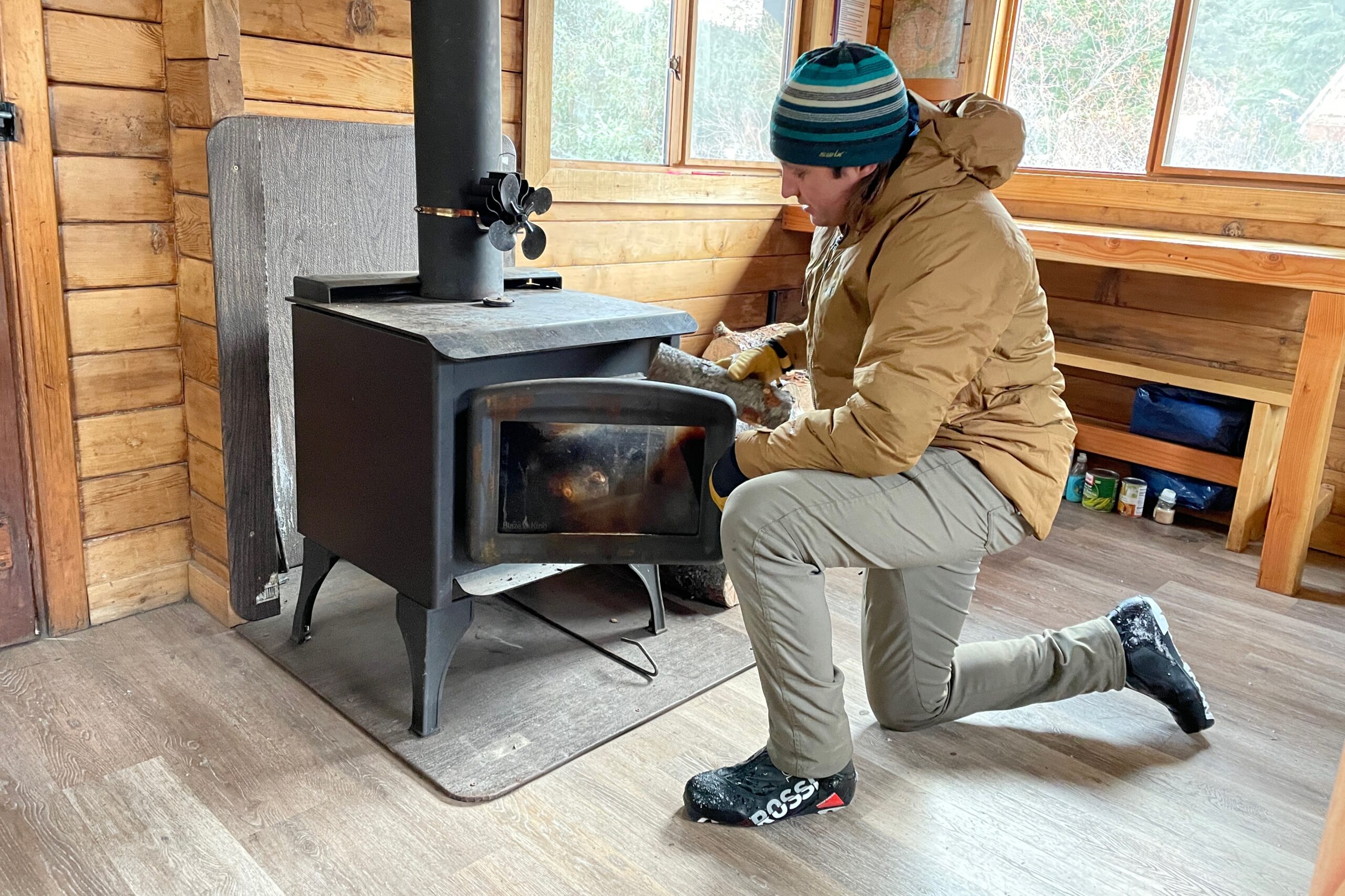 A man puts wood in a woodstove.