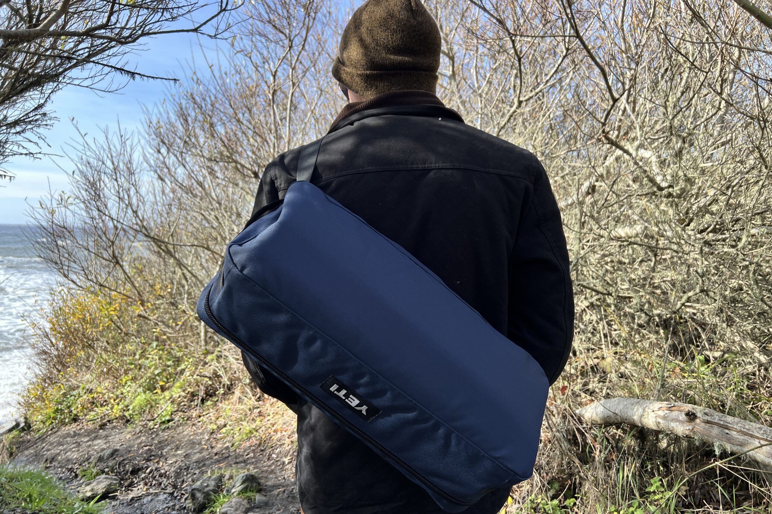 Man carrying the Yeti Lowlands Blanket using the shoulder strap on the carry case.