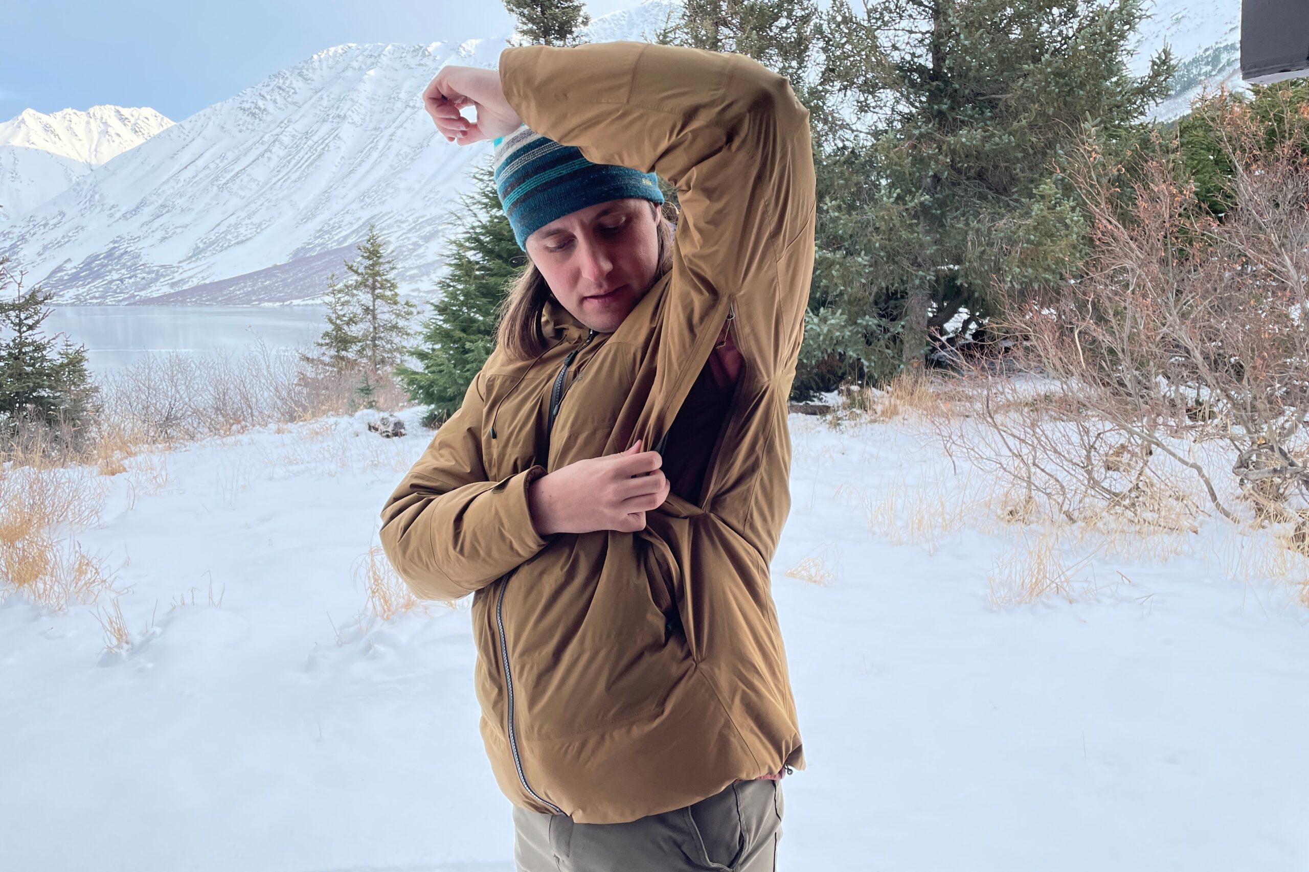 A man unzips the vents on his winter jacket.