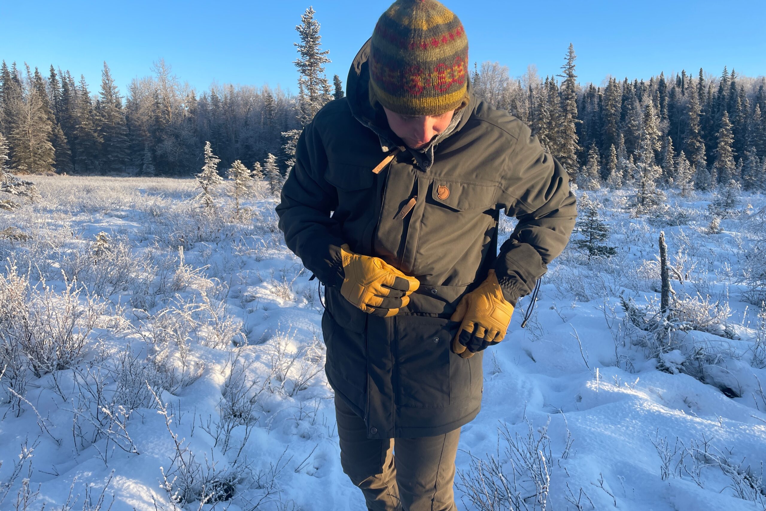 A man adjusts the pocket of his winter jacket.