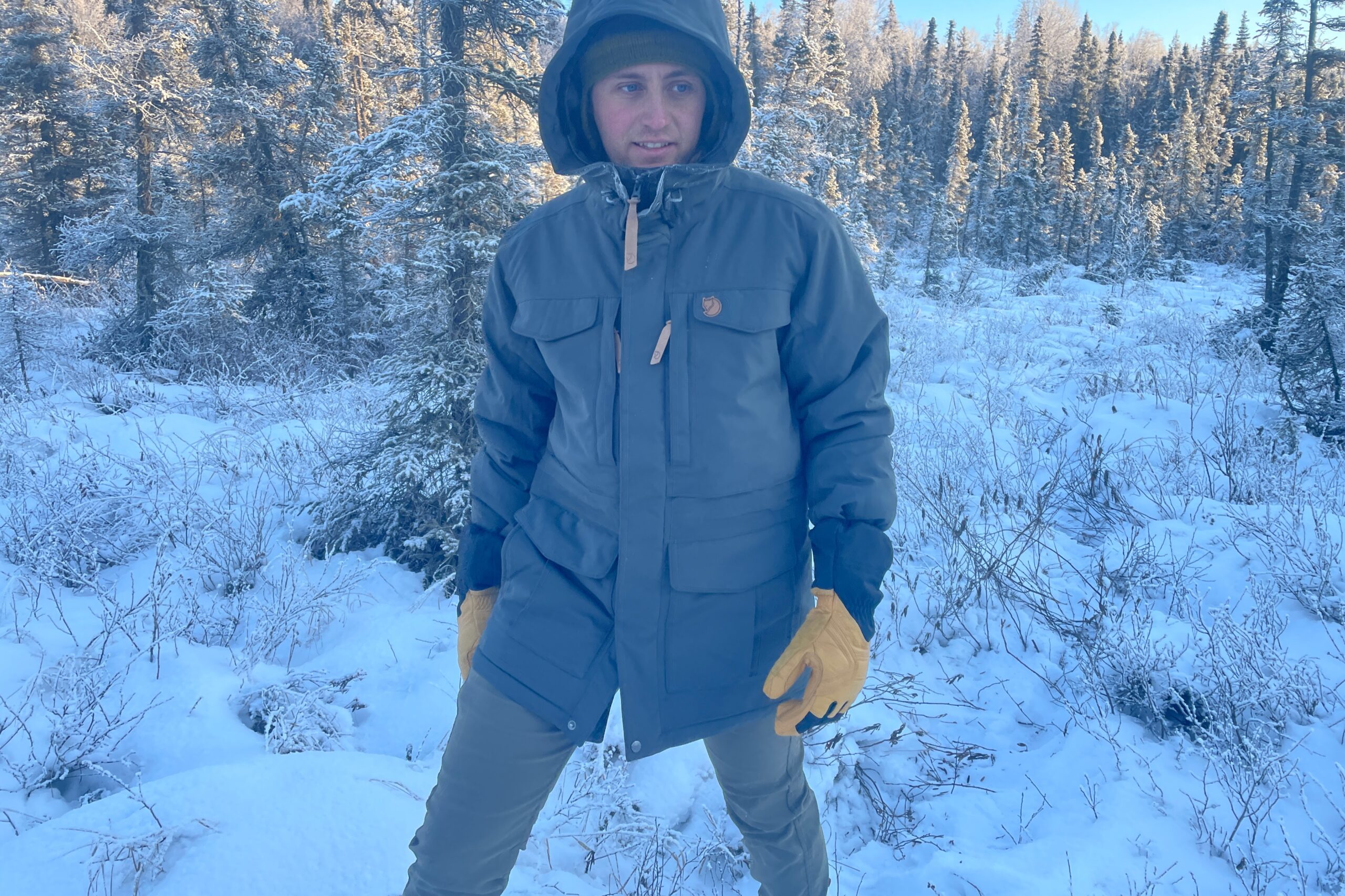 A man walks through a snowy forest.