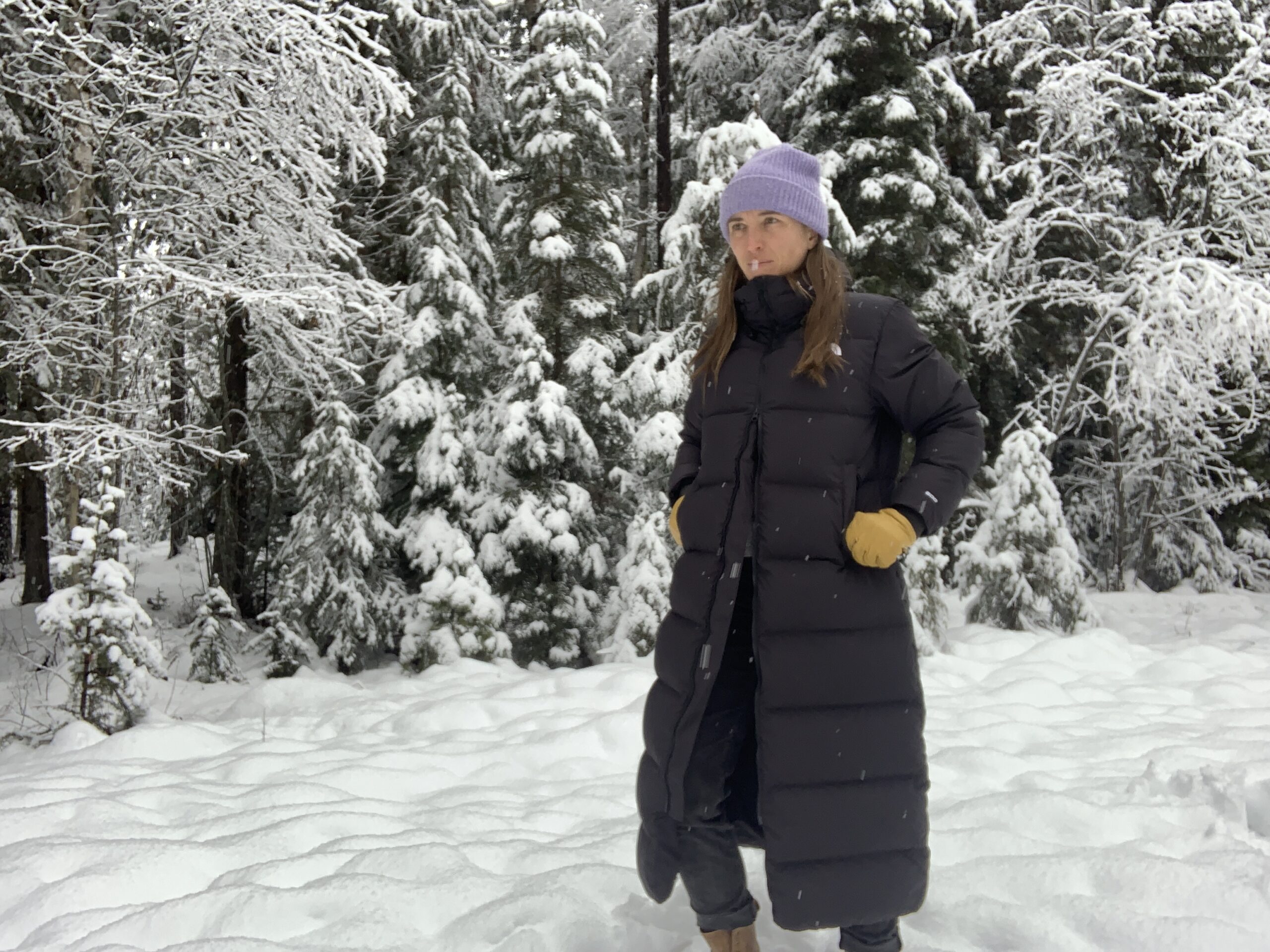 a woman walks through the snow with the north face triple c two way zipper unzipped from the bottom for ease of walking and ventilation