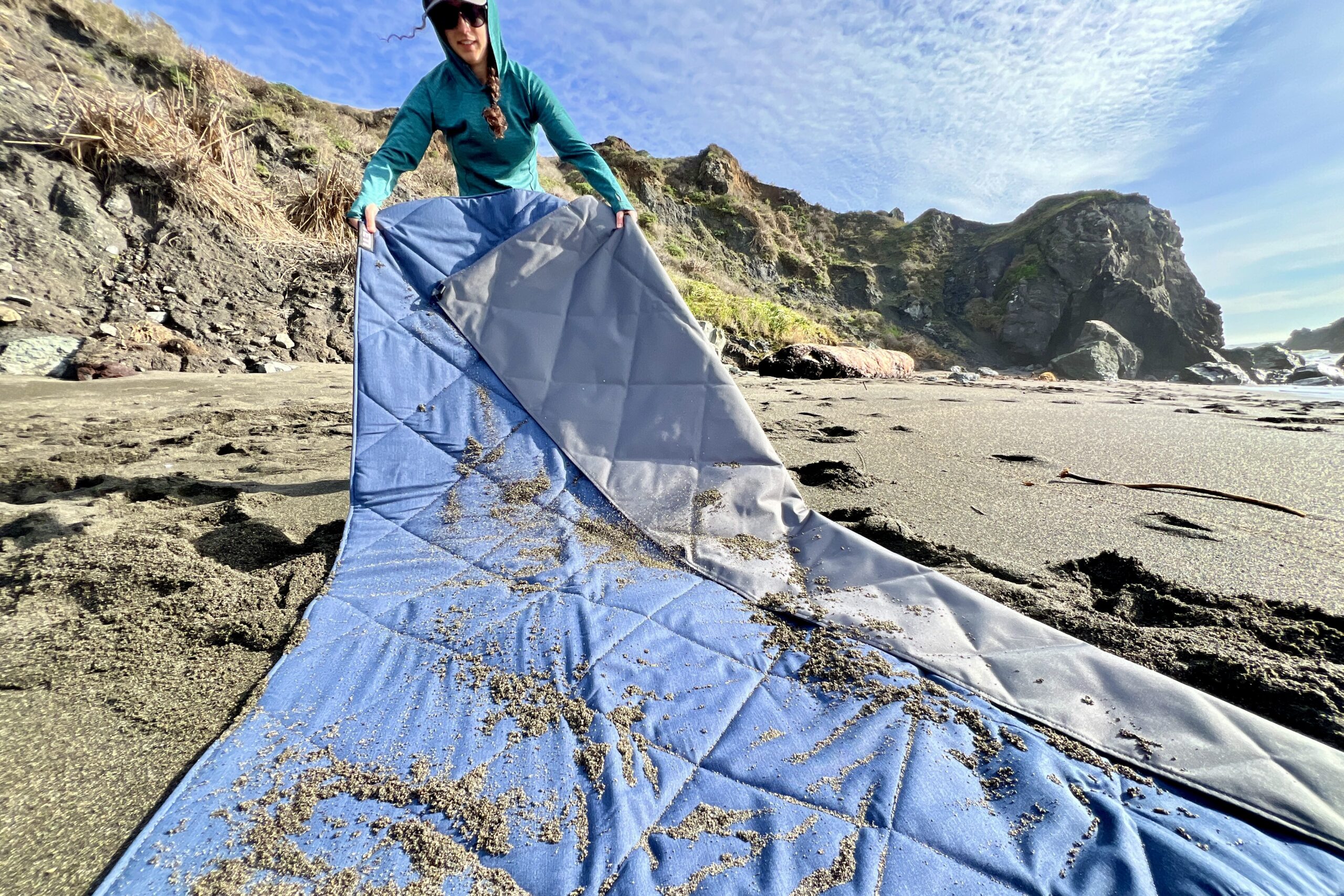 The Yeti Lowlands Blanket, covered in sand, is about to be tested during a “shake test” to see how debris clings to the fabric.