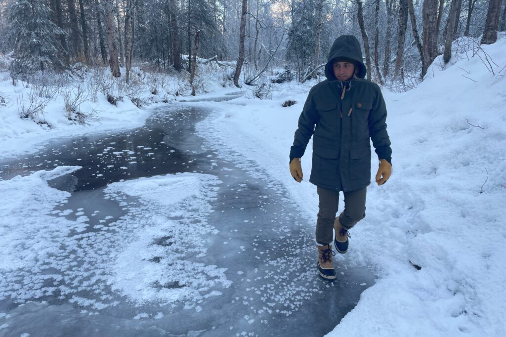 A man walks along an icy river