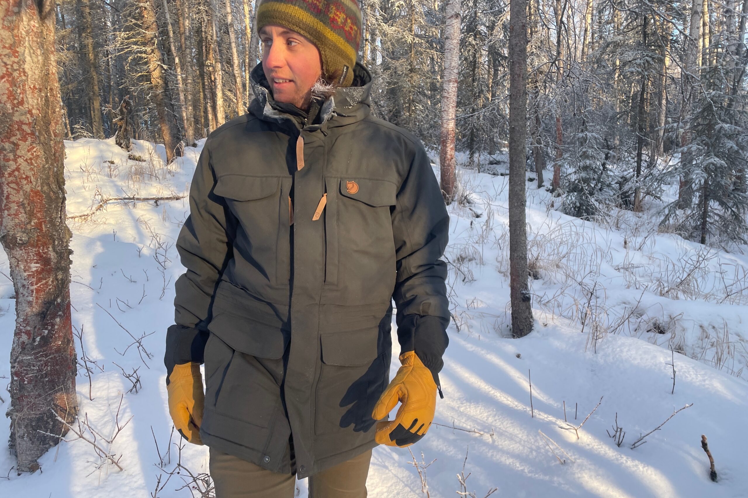 A man walks through sunshine in a snow covered forest