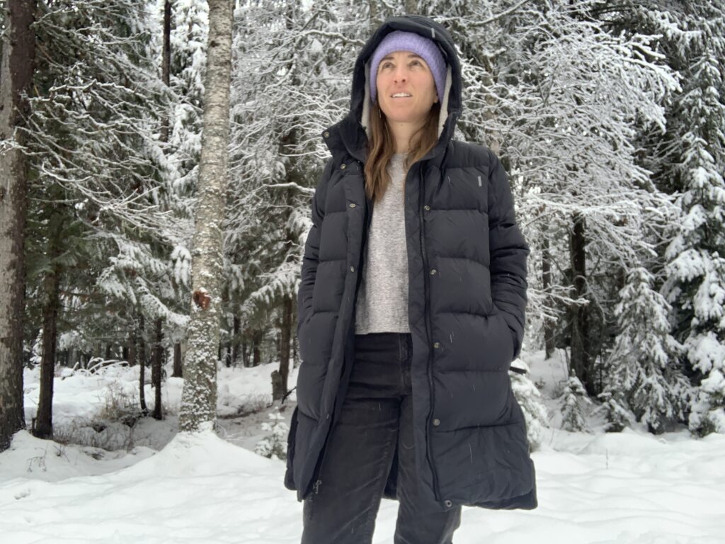 a woman with the REI norsland unzipped while its snowing