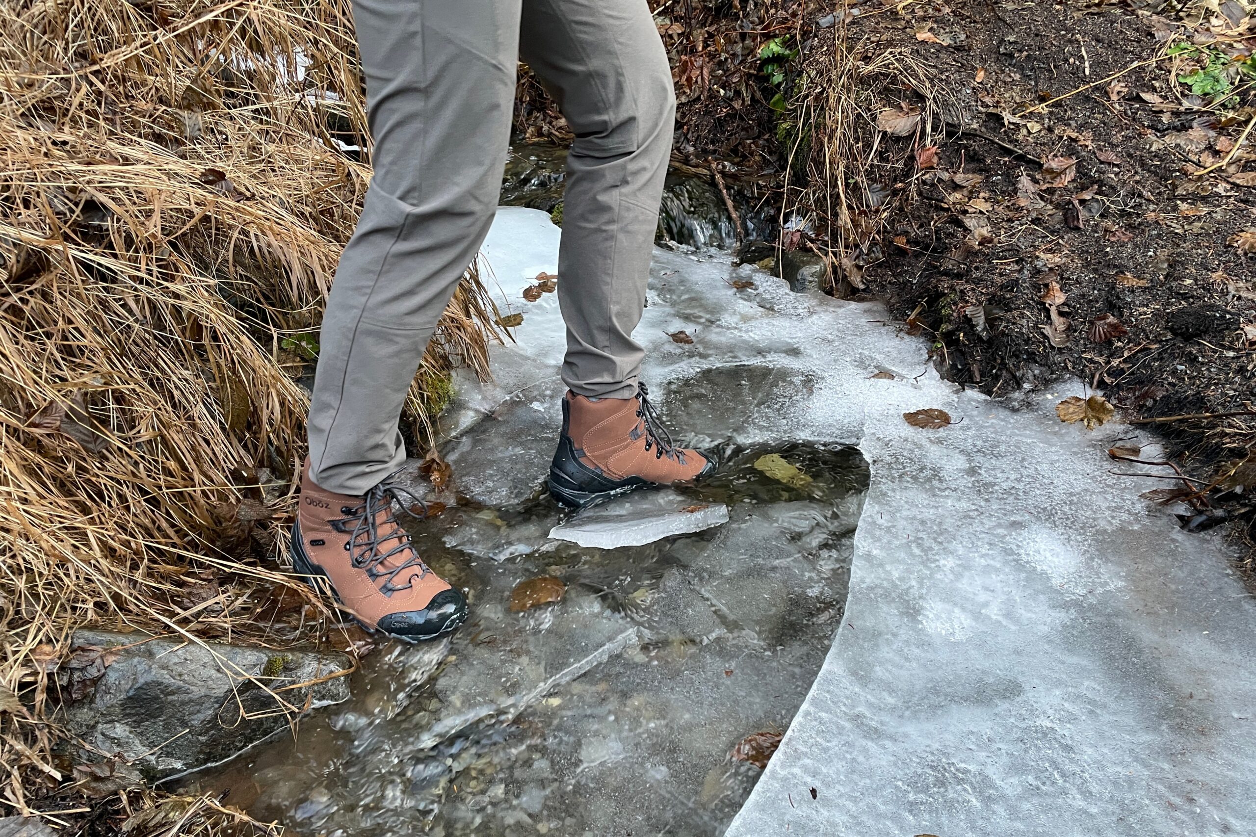 A closeup of boots submerged in an icy creek.