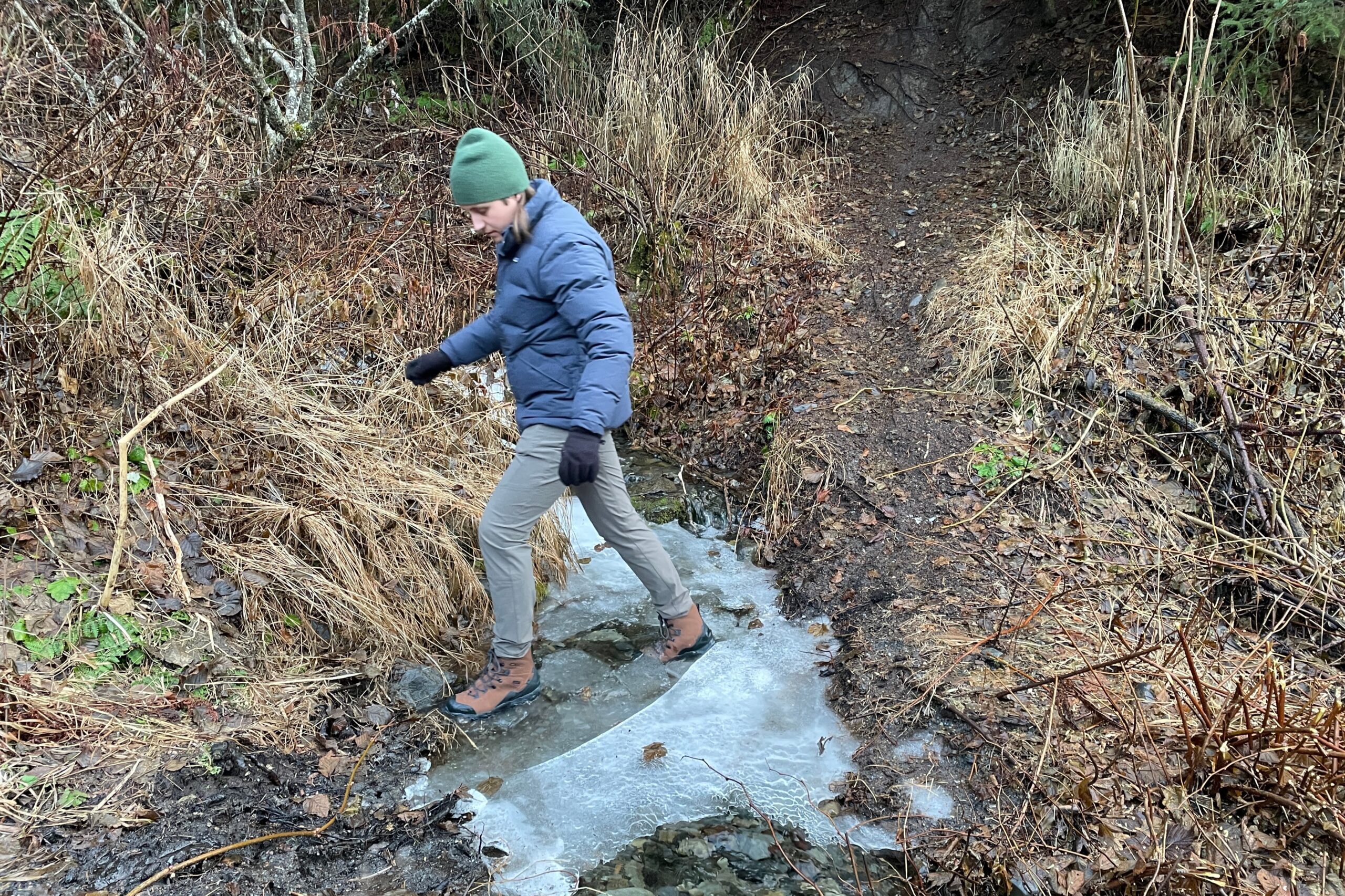 A man steps across a frozen creek.