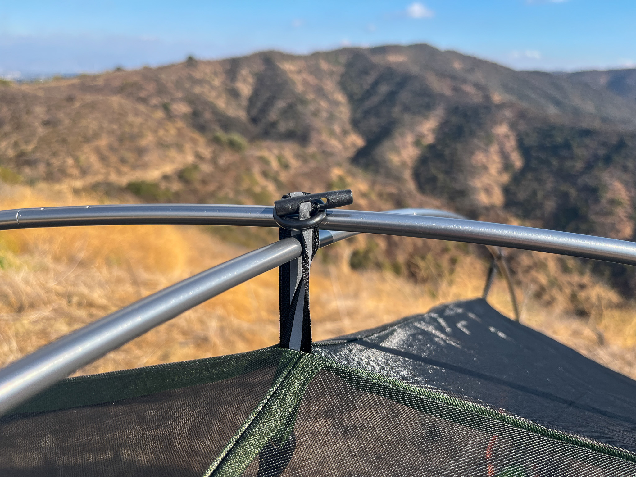 Closeup shot of the apex pole intersection and loop clip to hold it secure. Mountains and sky in the background.