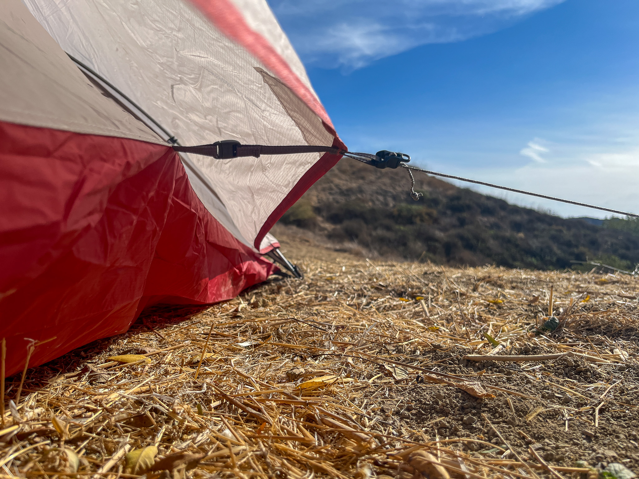 A closeup underside view of the rainfly where it clips to the inner tent's sidewall and guyed out.