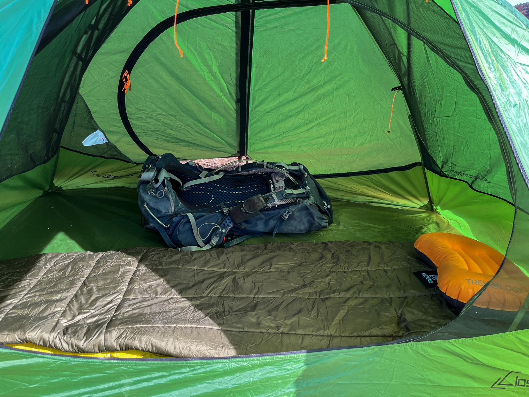 Interior view of the Clostnature Polaris 2 showing a backpack, sleeping bag, pillow, and the opposite door of the tent with enclosed vestibule.